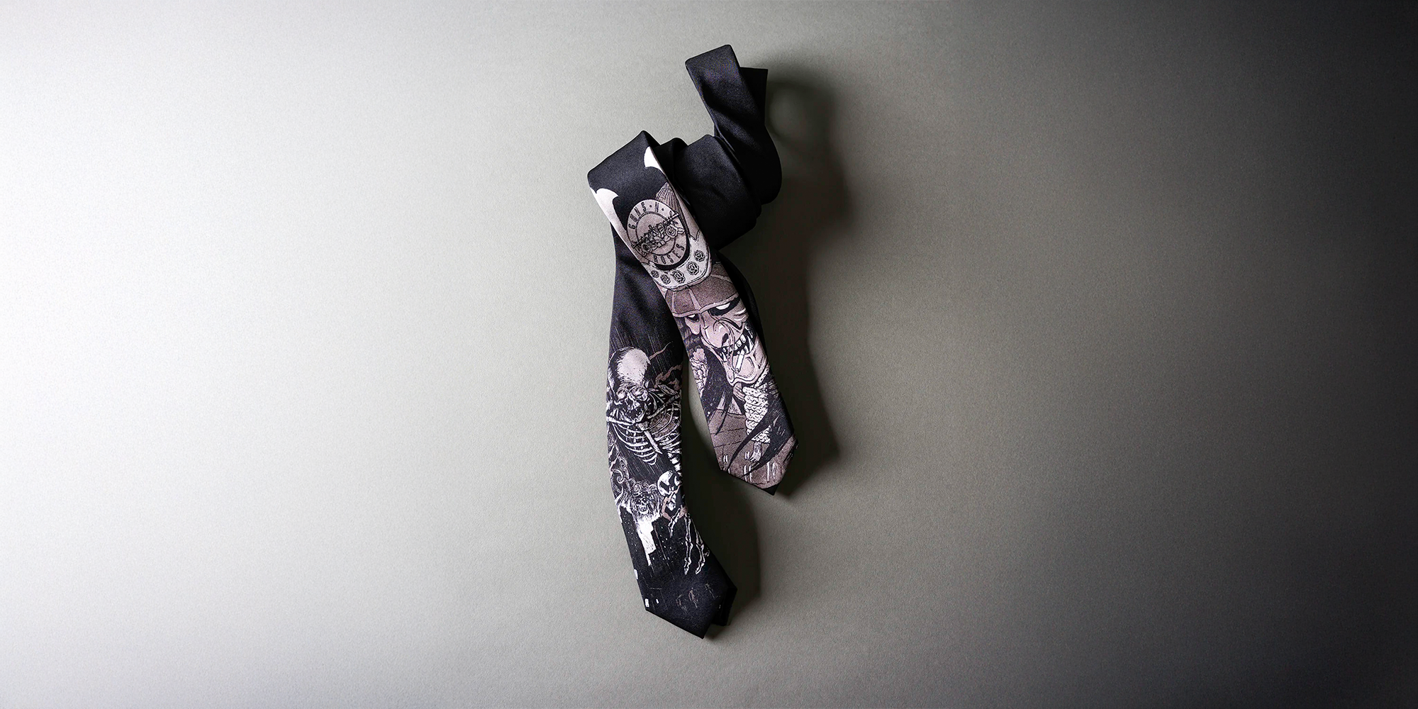Two black ties with graphic designs, one featuring a skeleton motif