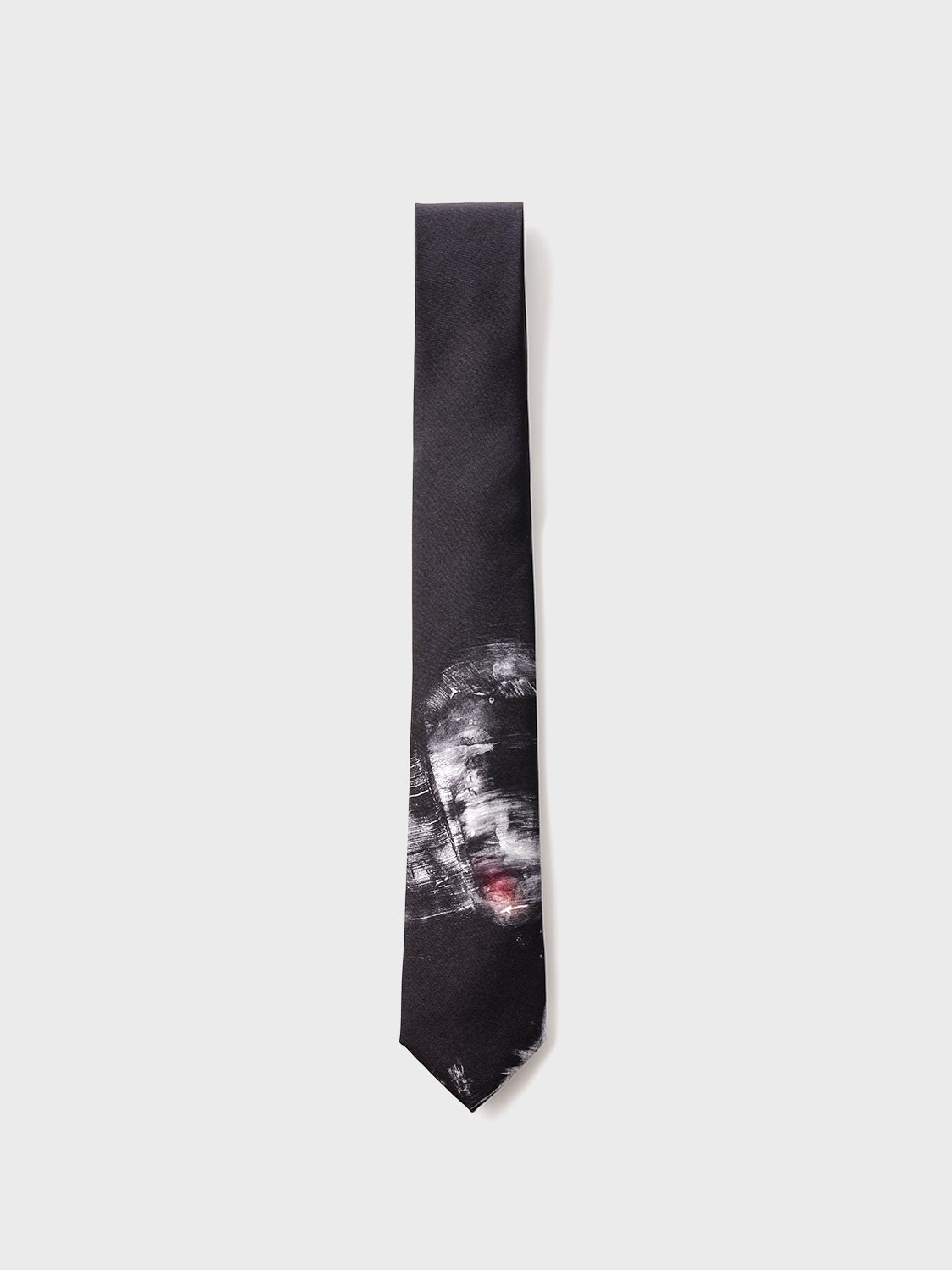 A neck tie with a dark background and a white abstract design featuring what appears to be a stylized face.