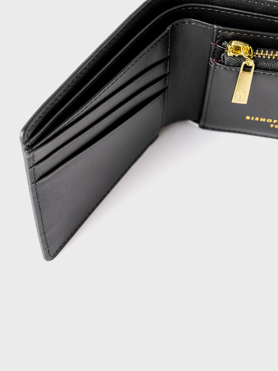 Black wallet with a gold zipper, shown open on a gray background.
