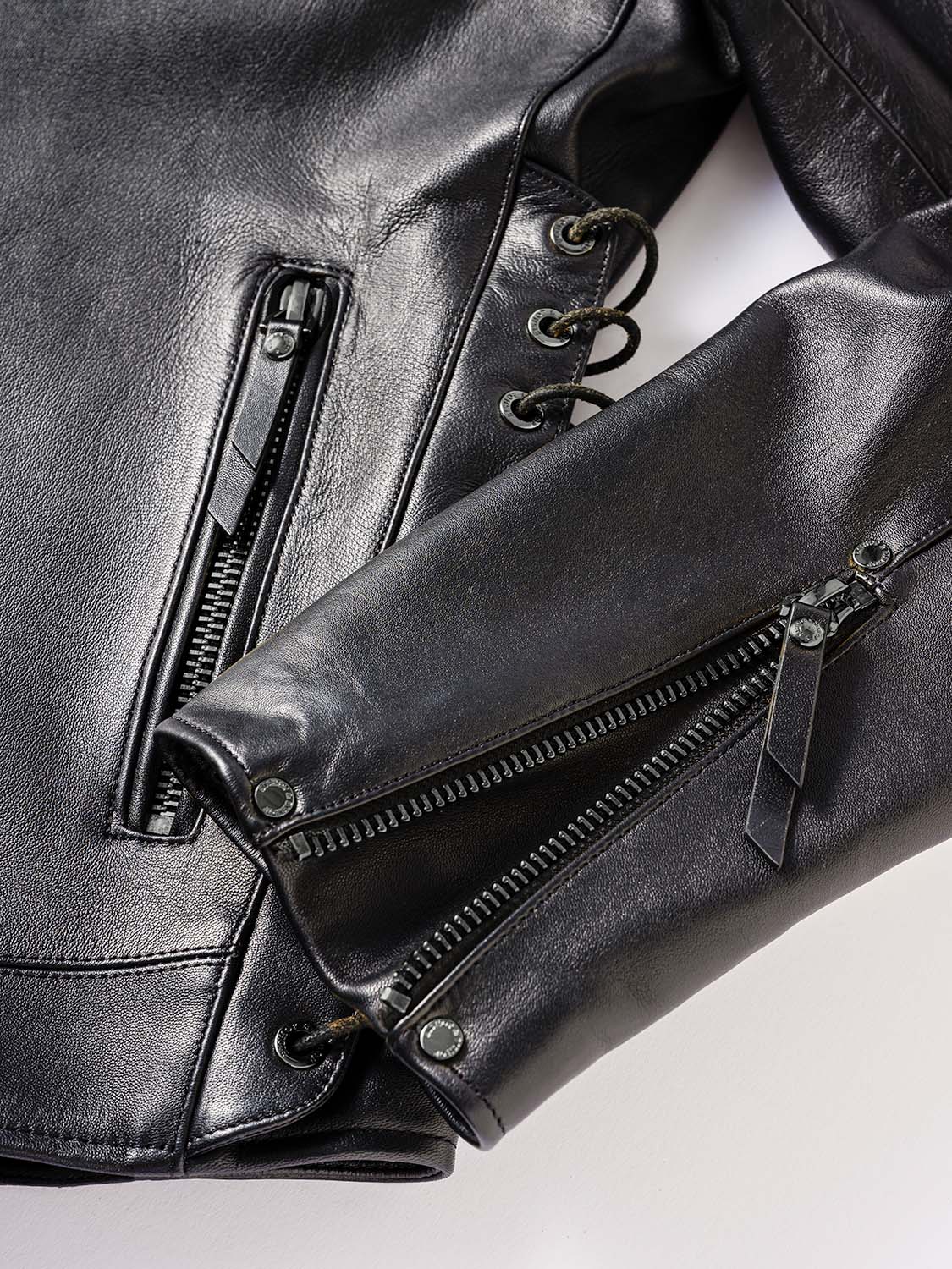 Close-up of the sleeve of a black leather jacket featuring a zipper.