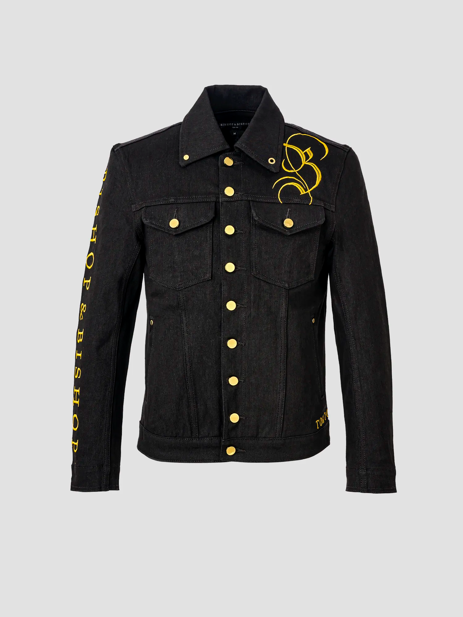 A black trucker jacket with gold Japanese embroidery and custom buttons, featuring a collar and decorative details on the sleeves.