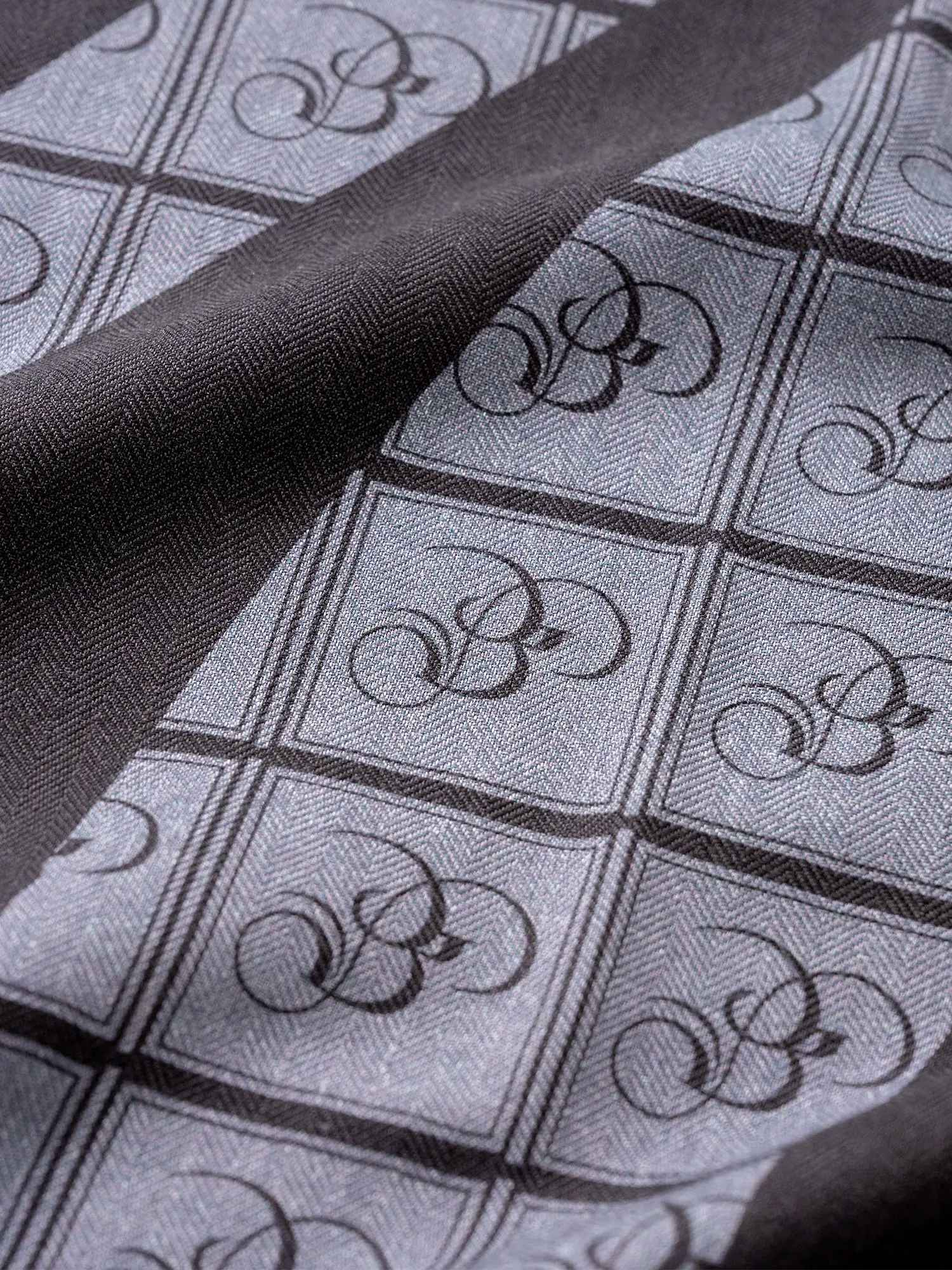 Close-up of a black and charcoal zebra print stole with the Bishop & Bishop monogram woven into the fabric.