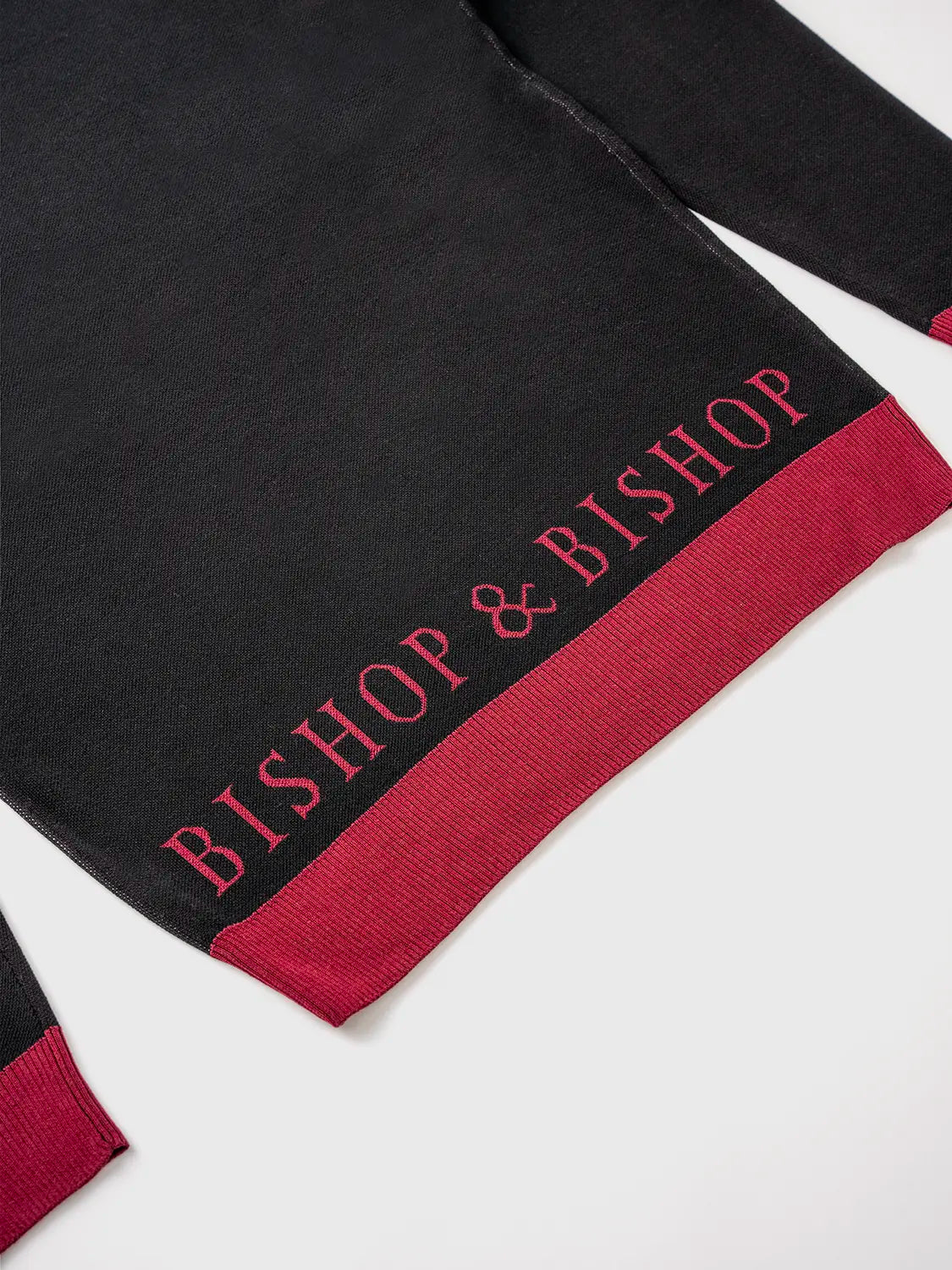 Black sweater with a red section at the bottom, featuring “Bishop & Bishop” text in red above the hem.