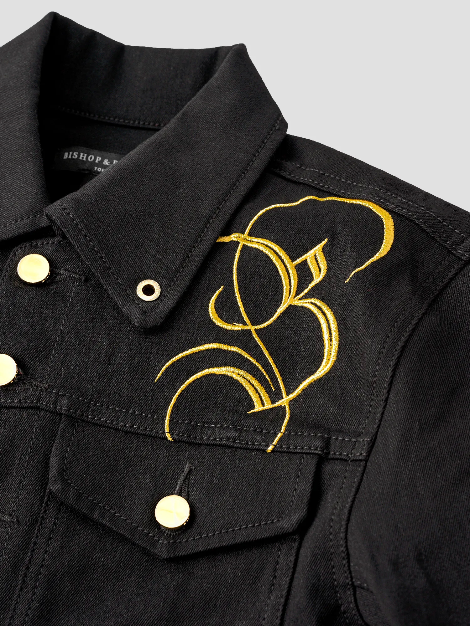 Black jacket with gold buttons and gold detailing on the shoulder and chest, featuring a large Bishop & Bishop monogram on one side.