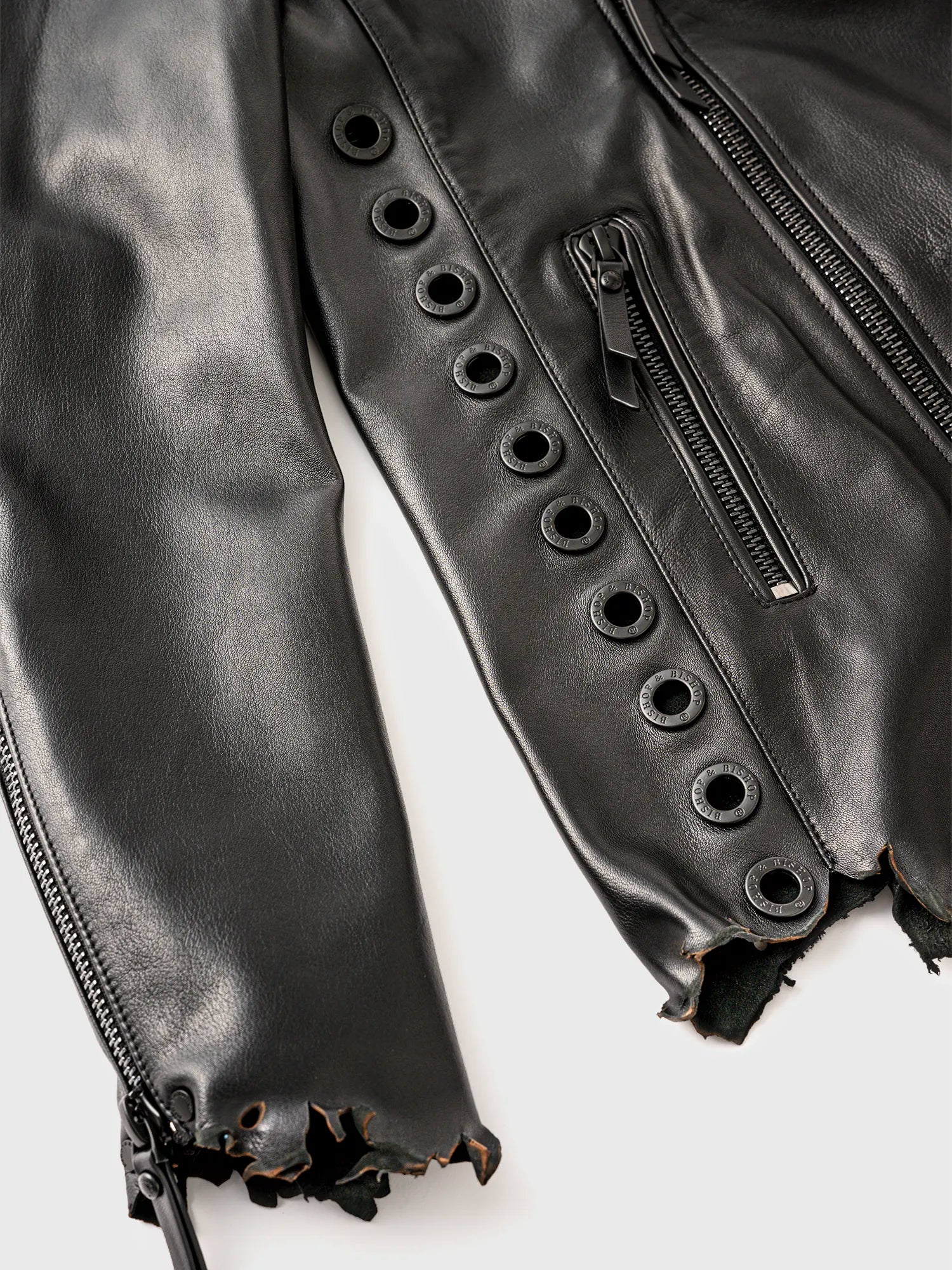 Close-up of the side of a black leather jacket with a distressed-style design and circular metal studs.