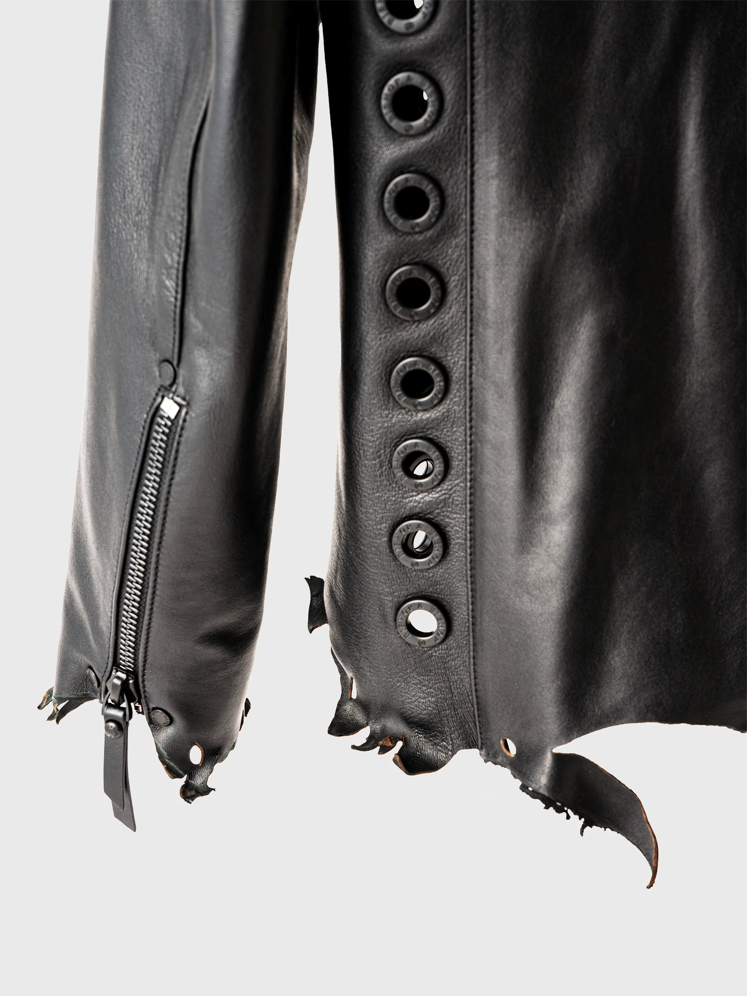 Close-up of the side of a black leather jacket with a distressed-style design and circular metal studs.