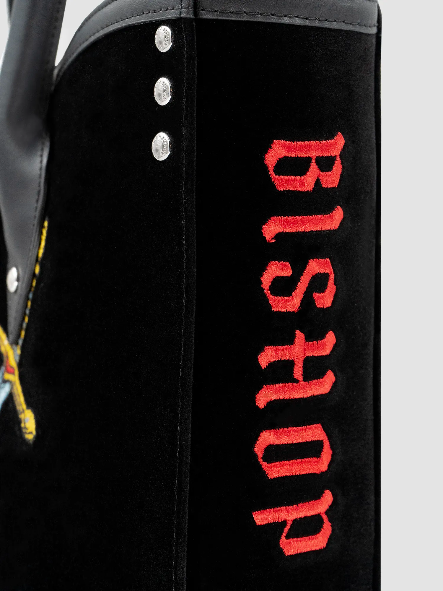 Close-up side view of the black velvet and leather tote bag, showing red “Bishop” lettering on the panel.