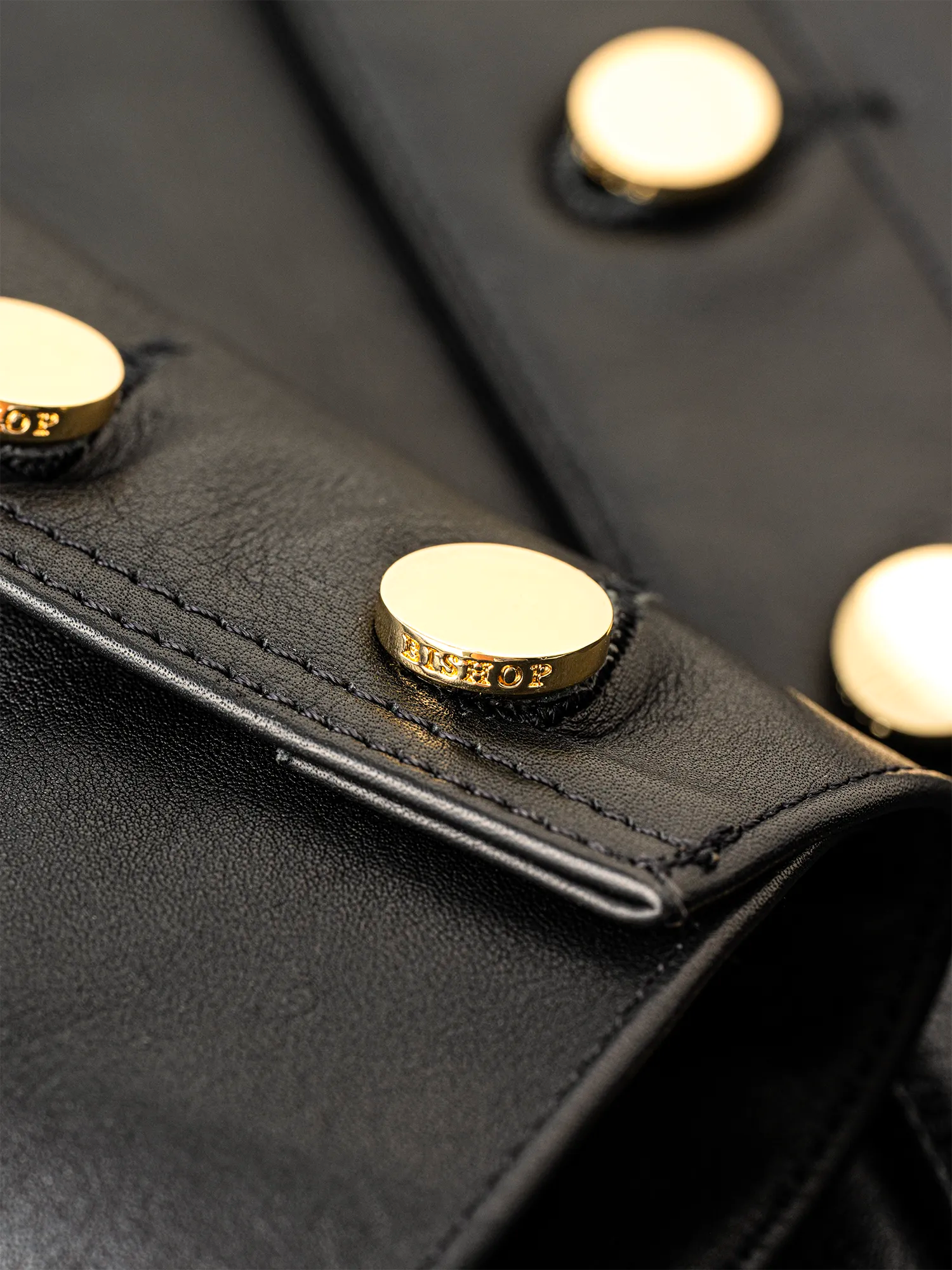 Close-up of gold buttons engraved with the word “Bishop.”