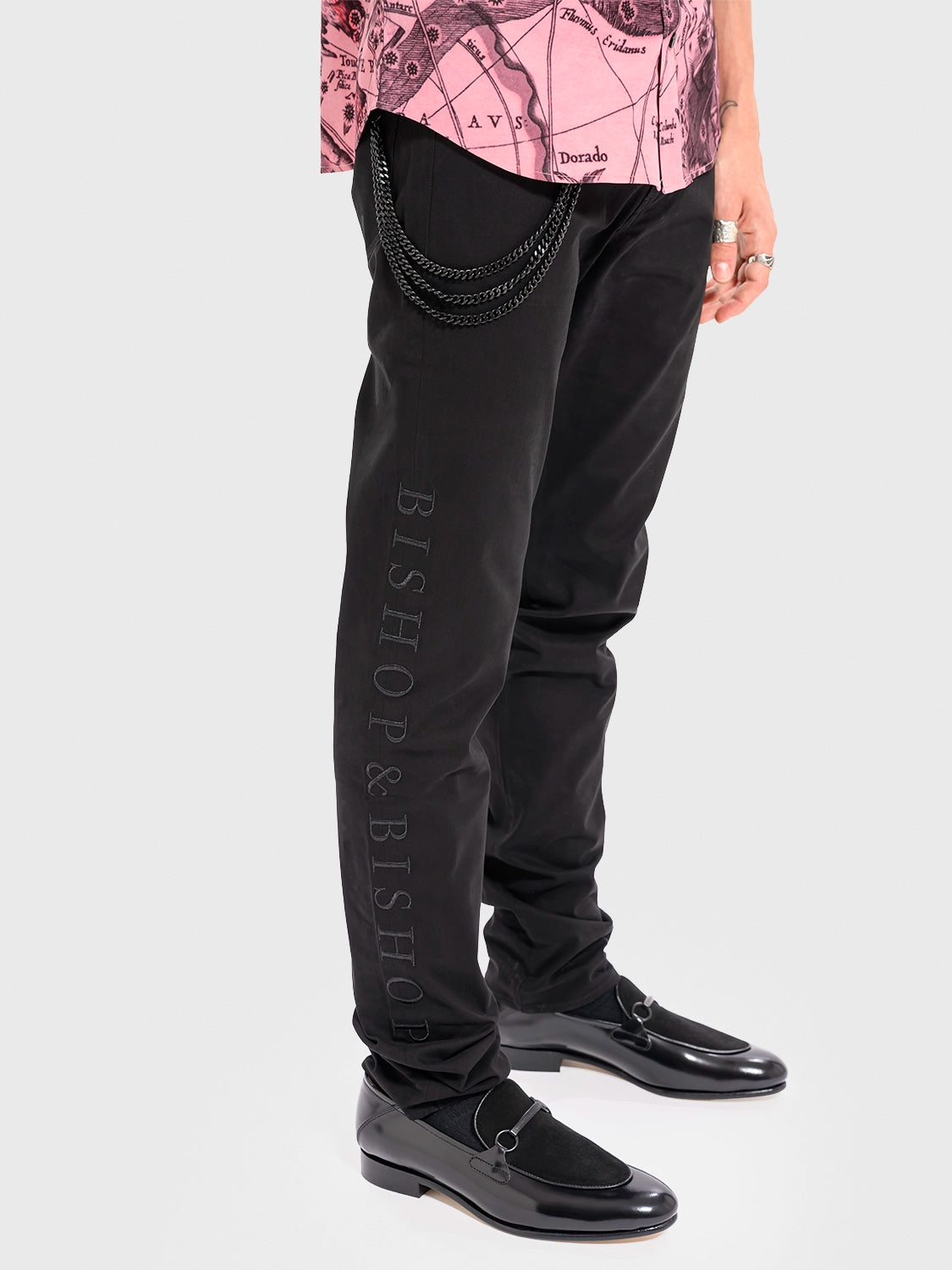 Person wearing black Bishop & Bishop pants with a pink patterned top on a white background