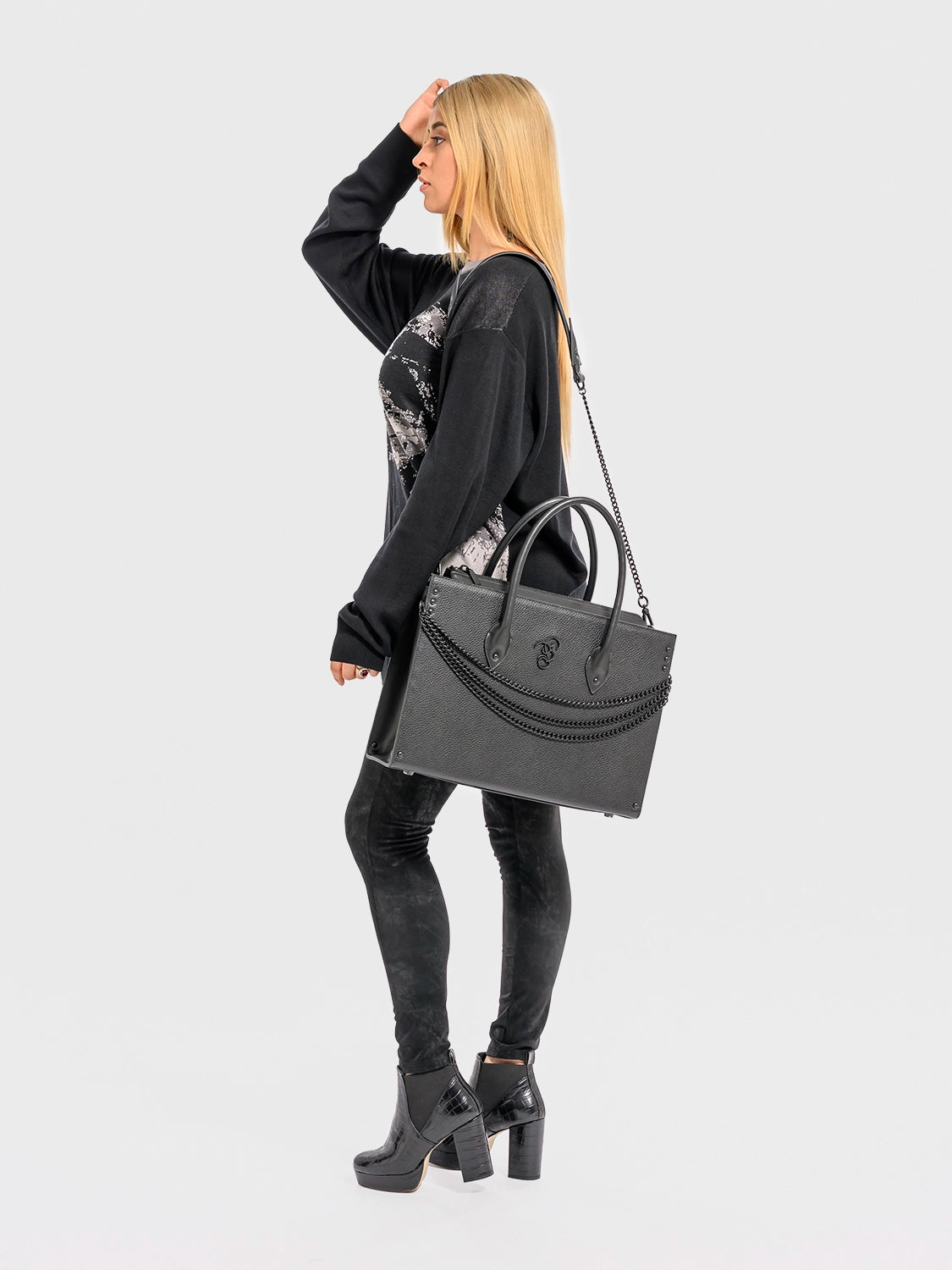 Woman holding a black handbag against a white background