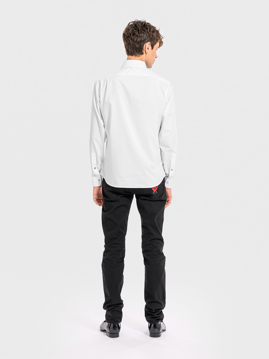 Person wearing a white shirt and black pants on a white background