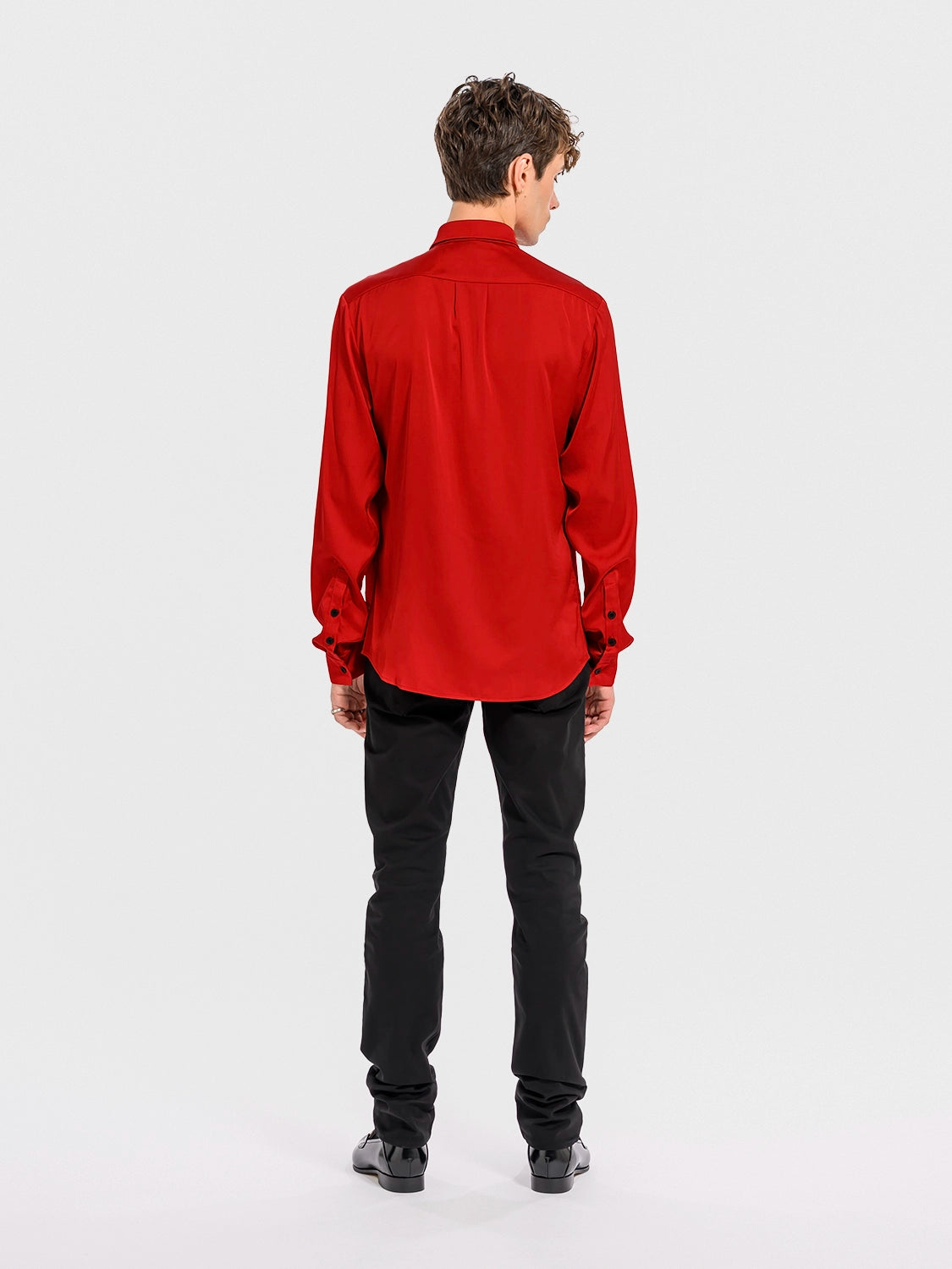 Person wearing a red shirt and black pants on a white background