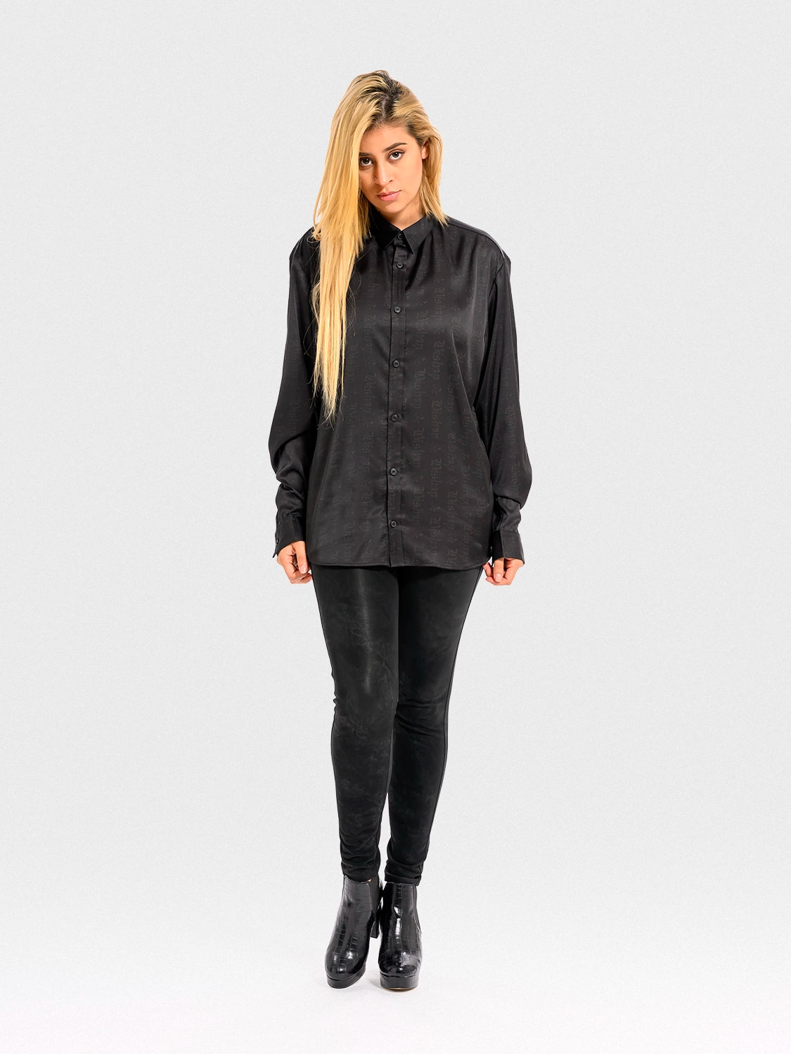 Woman wearing a black satin shirt and black pants on a white background