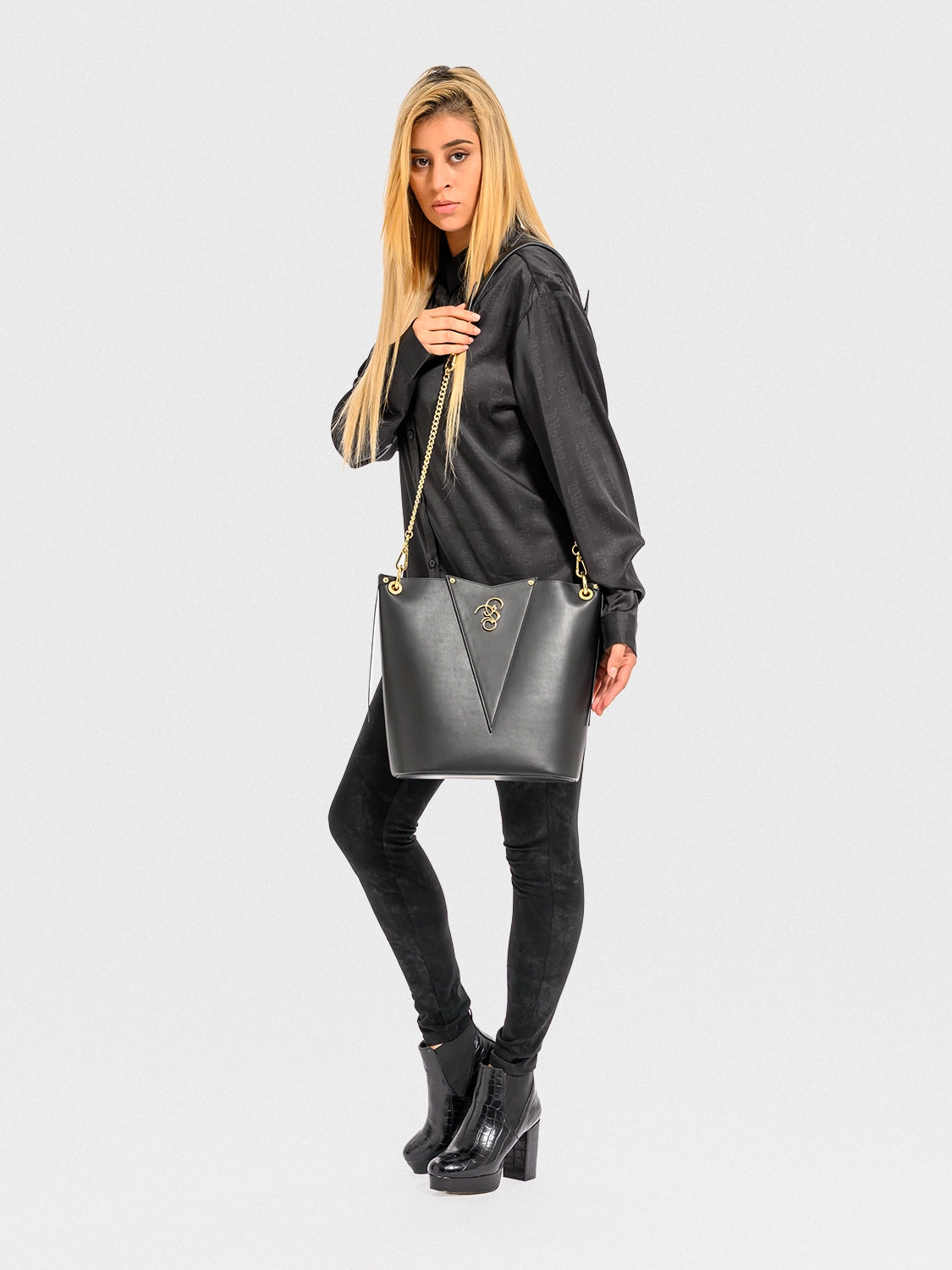 Woman holding a black handbag against a white background