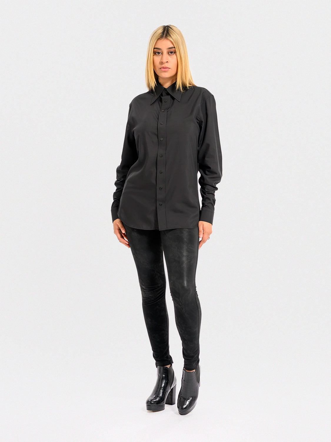Person wearing a black shirt and black pants on a white background