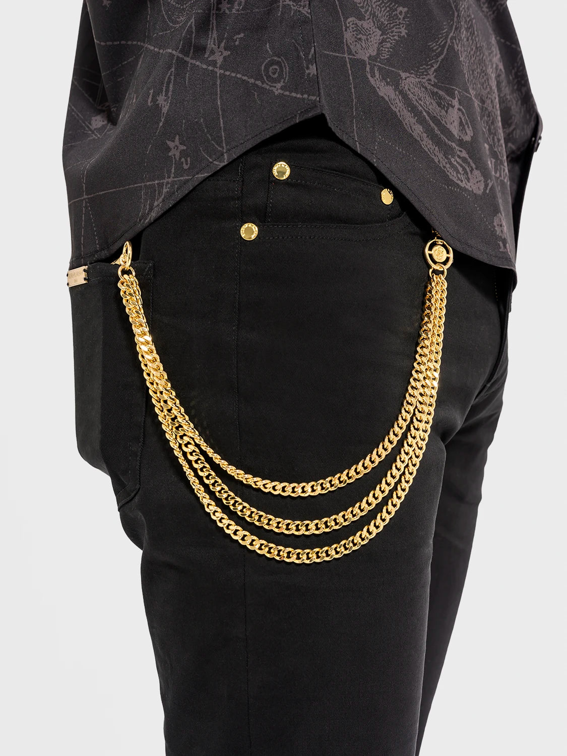 Black pants with gold chain detail on a plain background