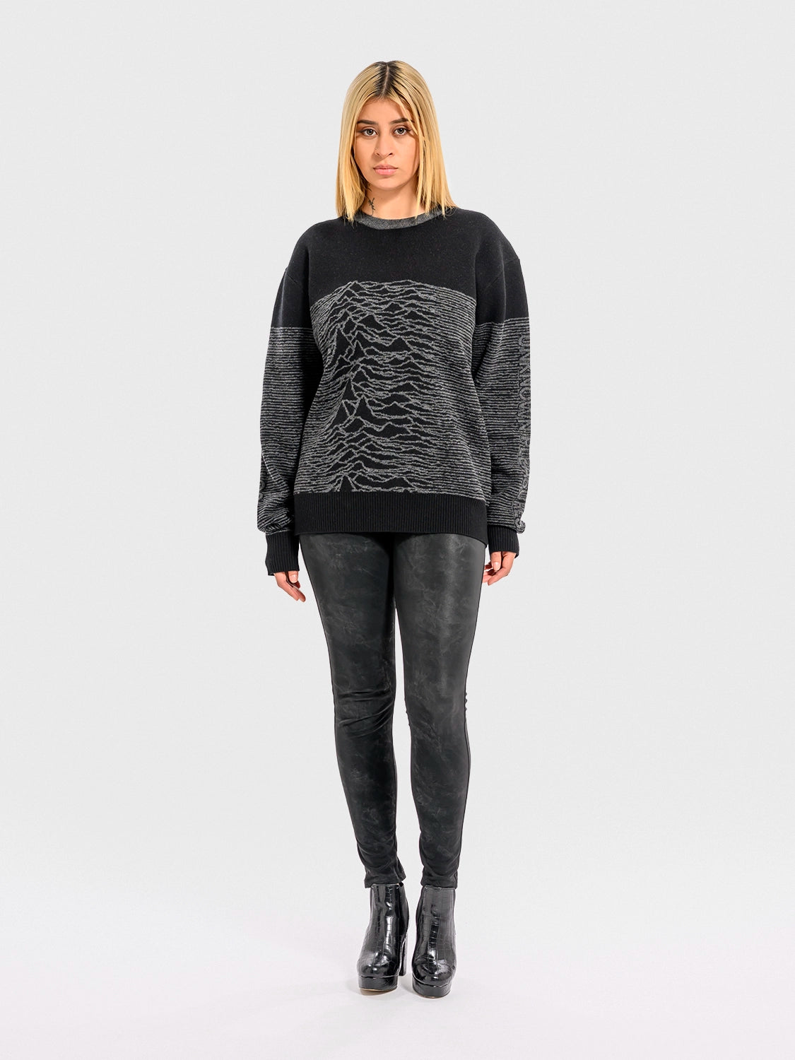 Woman wearing a black and gray sweater with a unique pattern on a white background