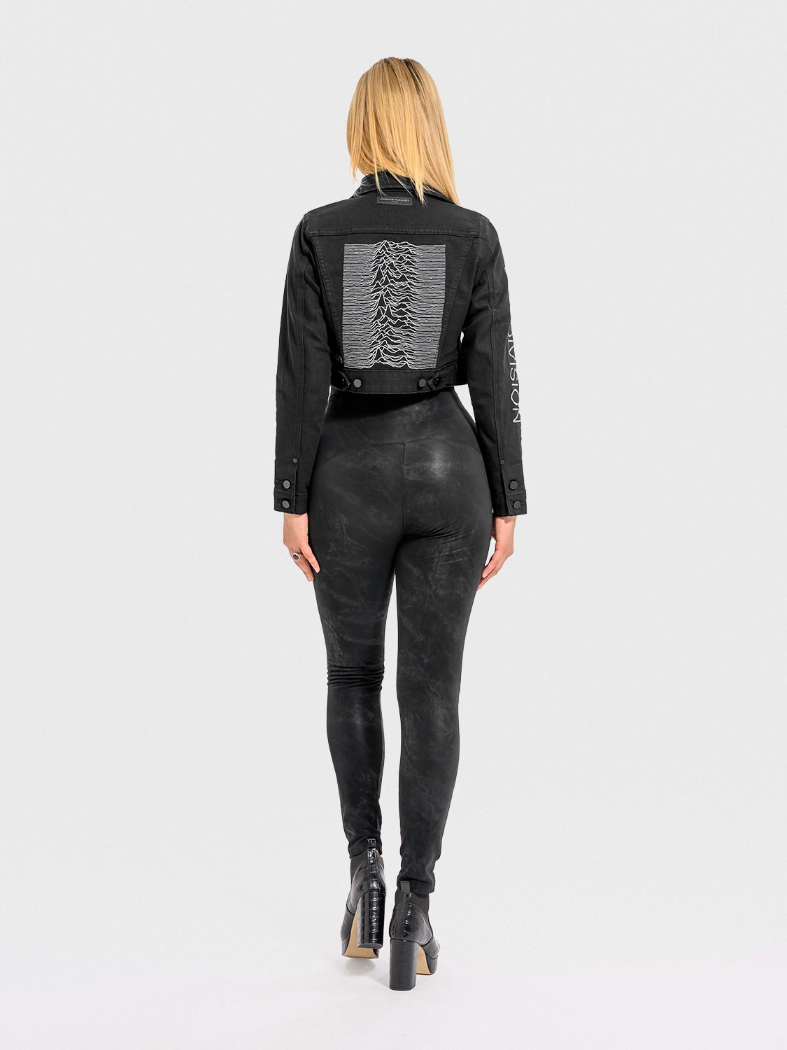 Person wearing a black outfit with a unique design on the back, standing against a white background.