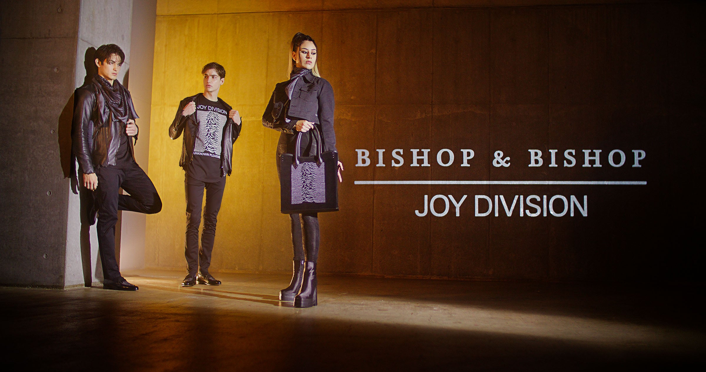Group of people wearing outfits with Joy Division graphics, posing together, with “Bishop & Bishop Joy Division” overlaid on the image.
