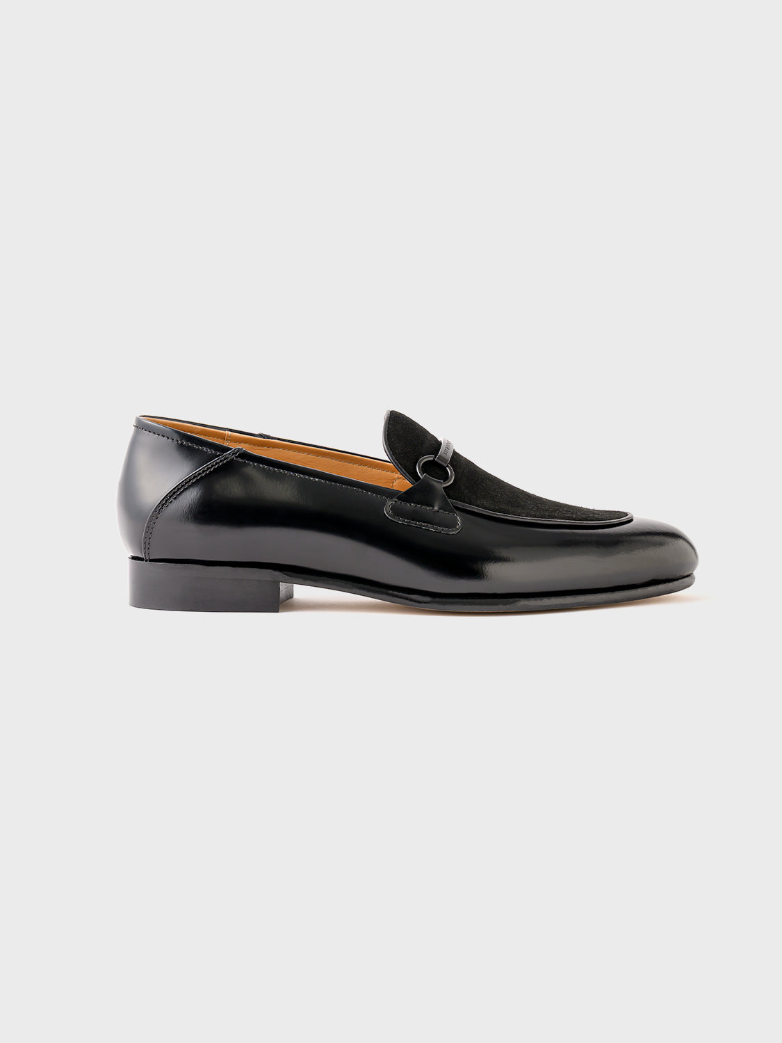 Side view of a single black leather loafer, emphasizing its clean silhouette and matte finish.