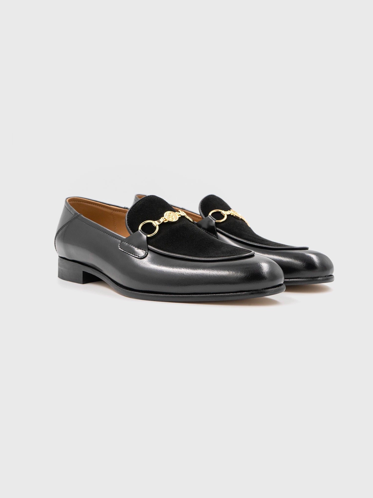A pair of black leather loafers with a gold-toned horsebit detail on the front.