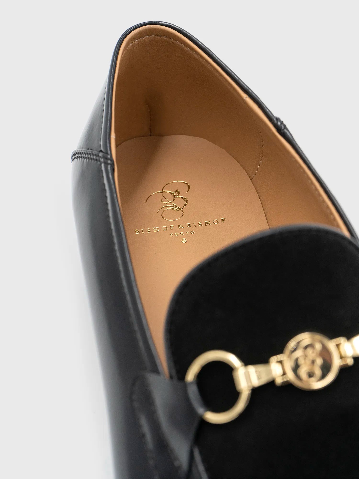 Close-up of a black shoe with gold detailing, showing “Bishop & Bishop Tokyo” printed inside.