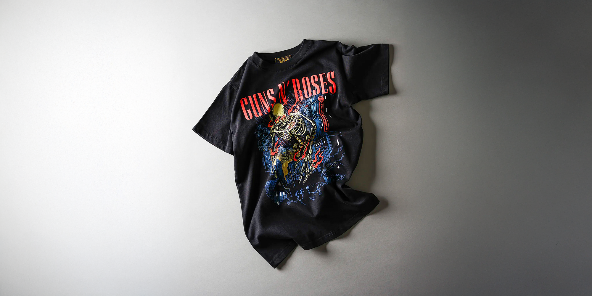 Black T-shirt featuring the red Guns N’ Roses logo and a skeleton graphic, displayed on a white background.