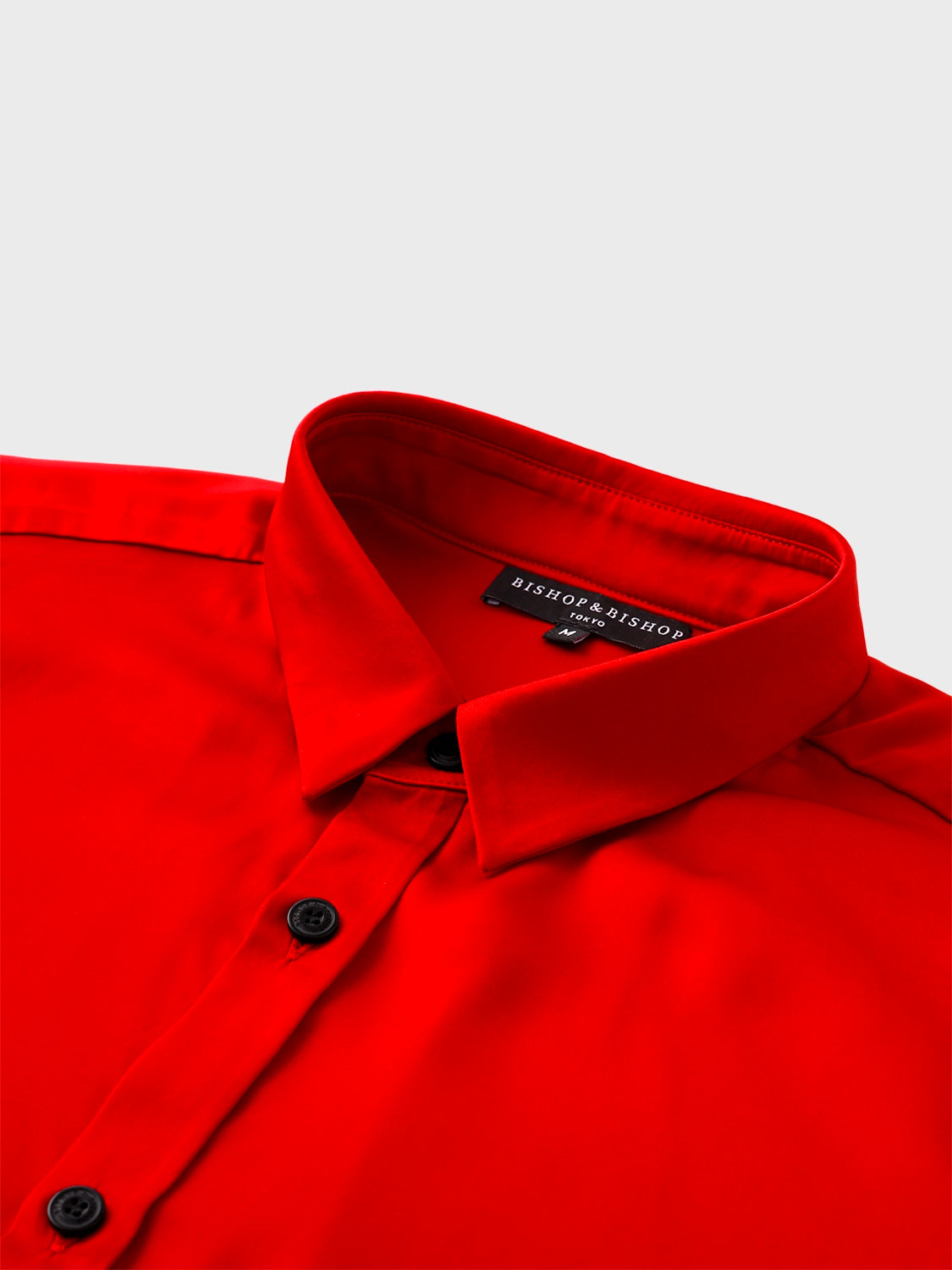 Close-up of the collar area of the red silk shirt, revealing fine stitching and rich silk texture.