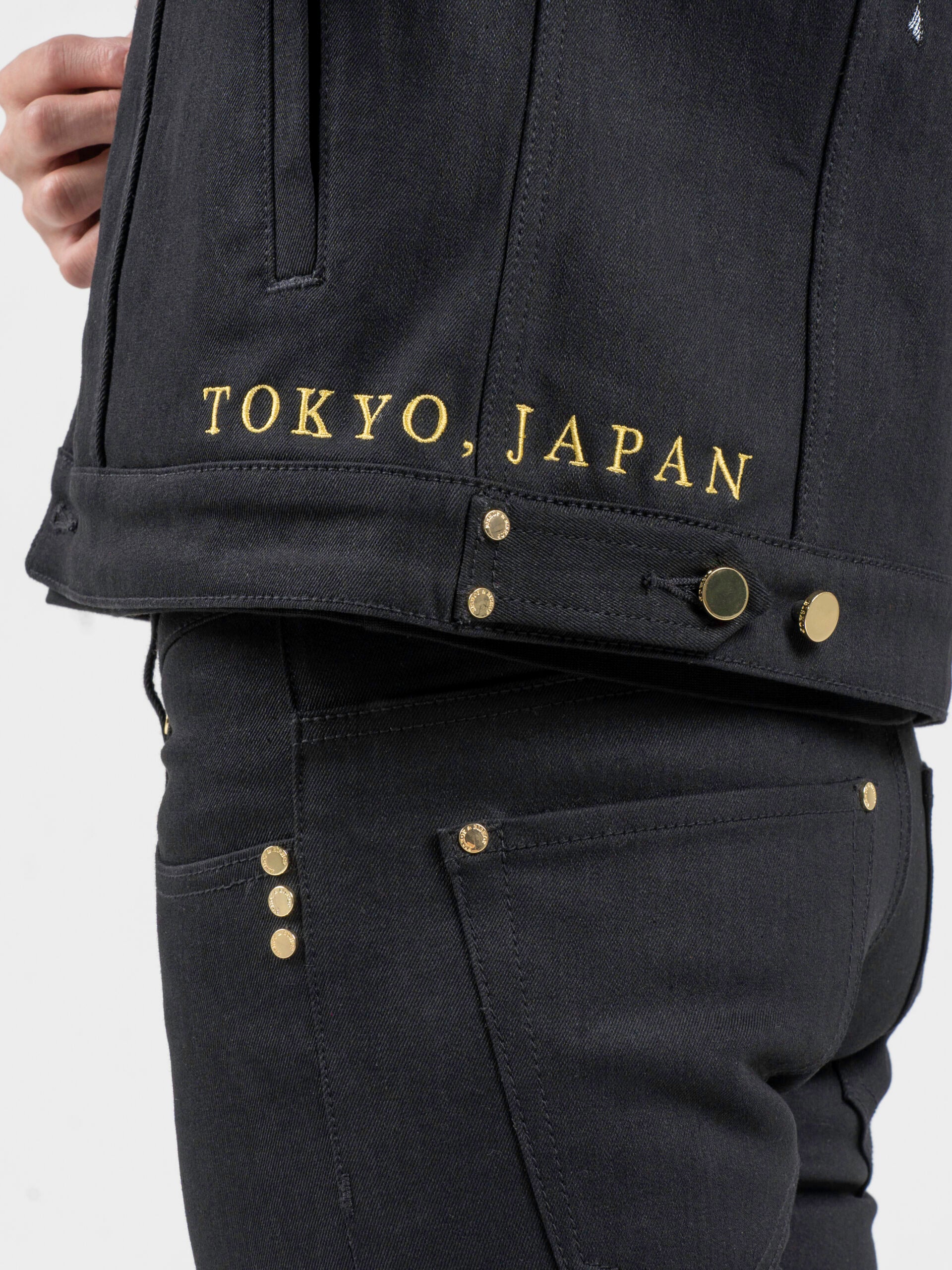 Side view of a black jacket with “Tokyo Japan” text printed near the hem.