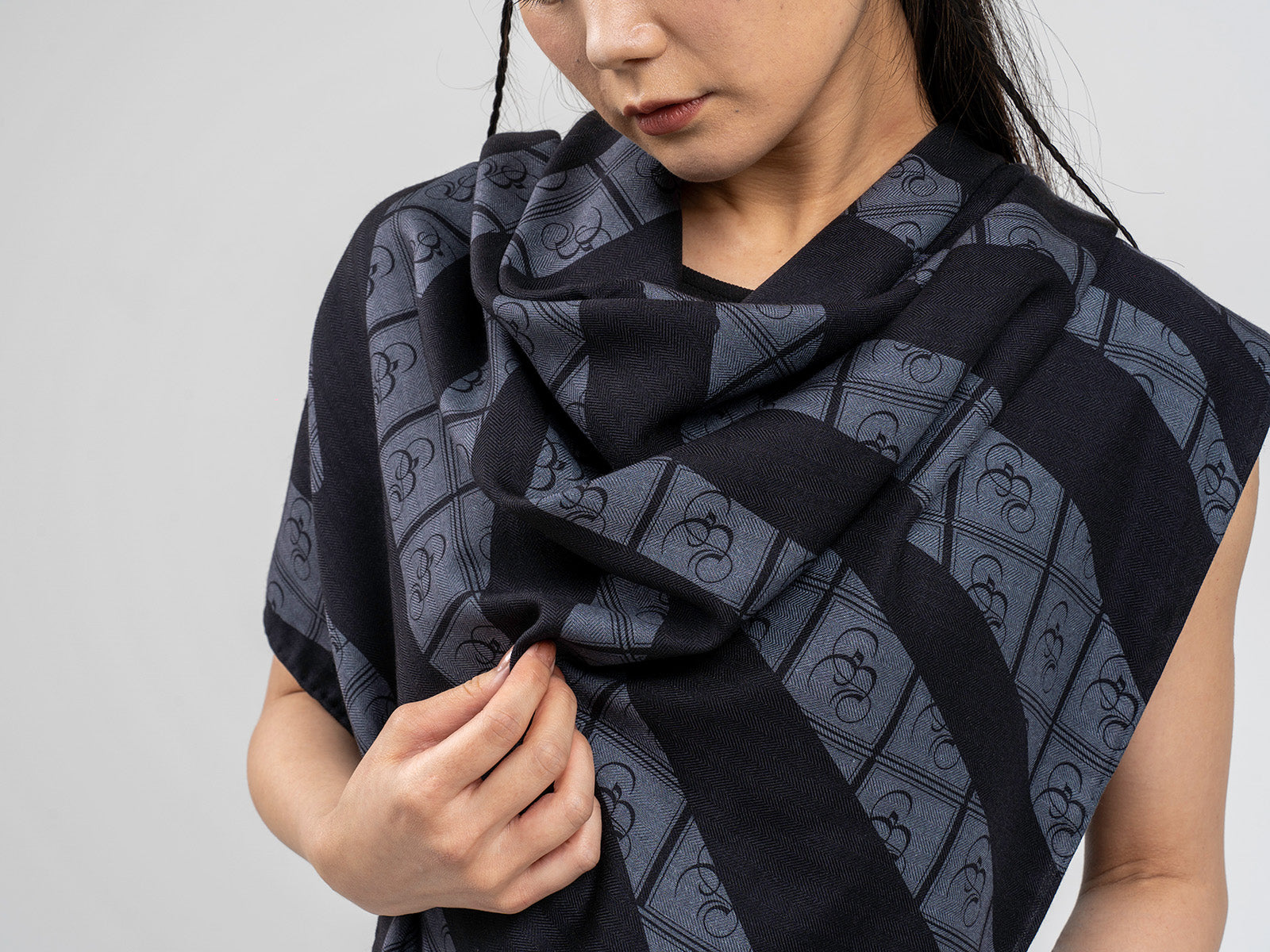 Close-up of a black and grey scarf featuring a repeating Bishop & Bishop logo pattern.
