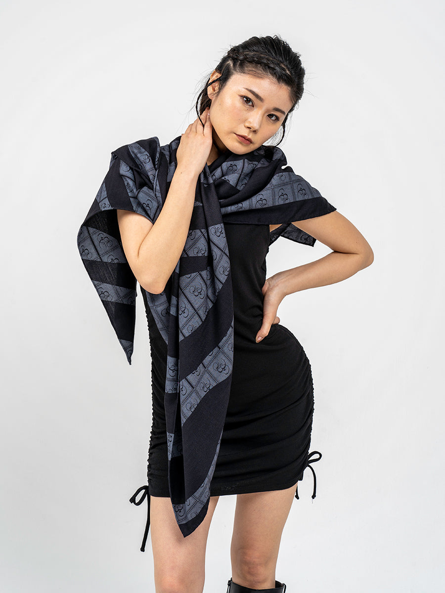 Person wearing a black and charcoal zebra print stole with the Bishop & Bishop monogram woven into the fabric.
