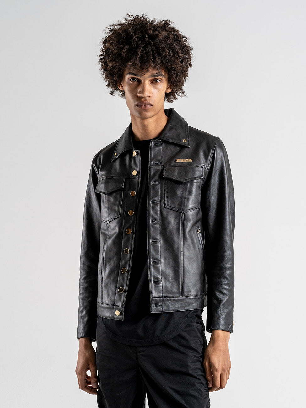 Man wearing a black leather jacket with gold buttons
