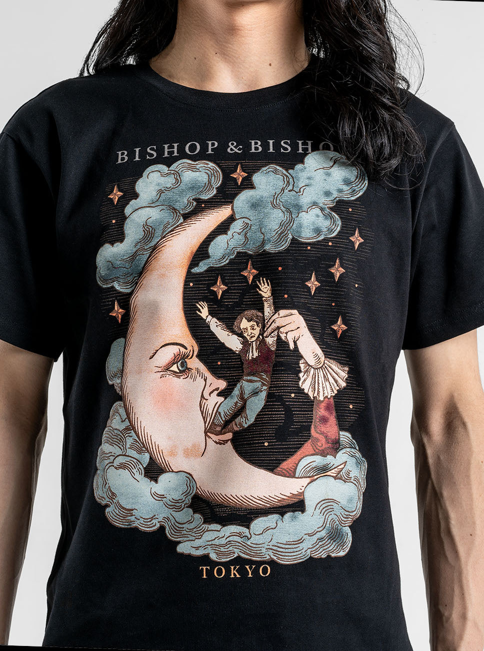 Person wearing a black T-shirt with a graphic print of a moon and a figure in an angry pose, with the text “BISHOP & BISHOP” above the design.