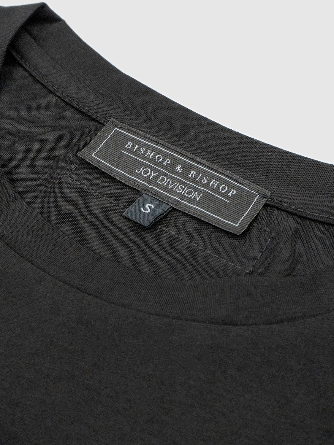 Close-up of the inner back collar showing the woven Joy Division label stitched into the neckline.