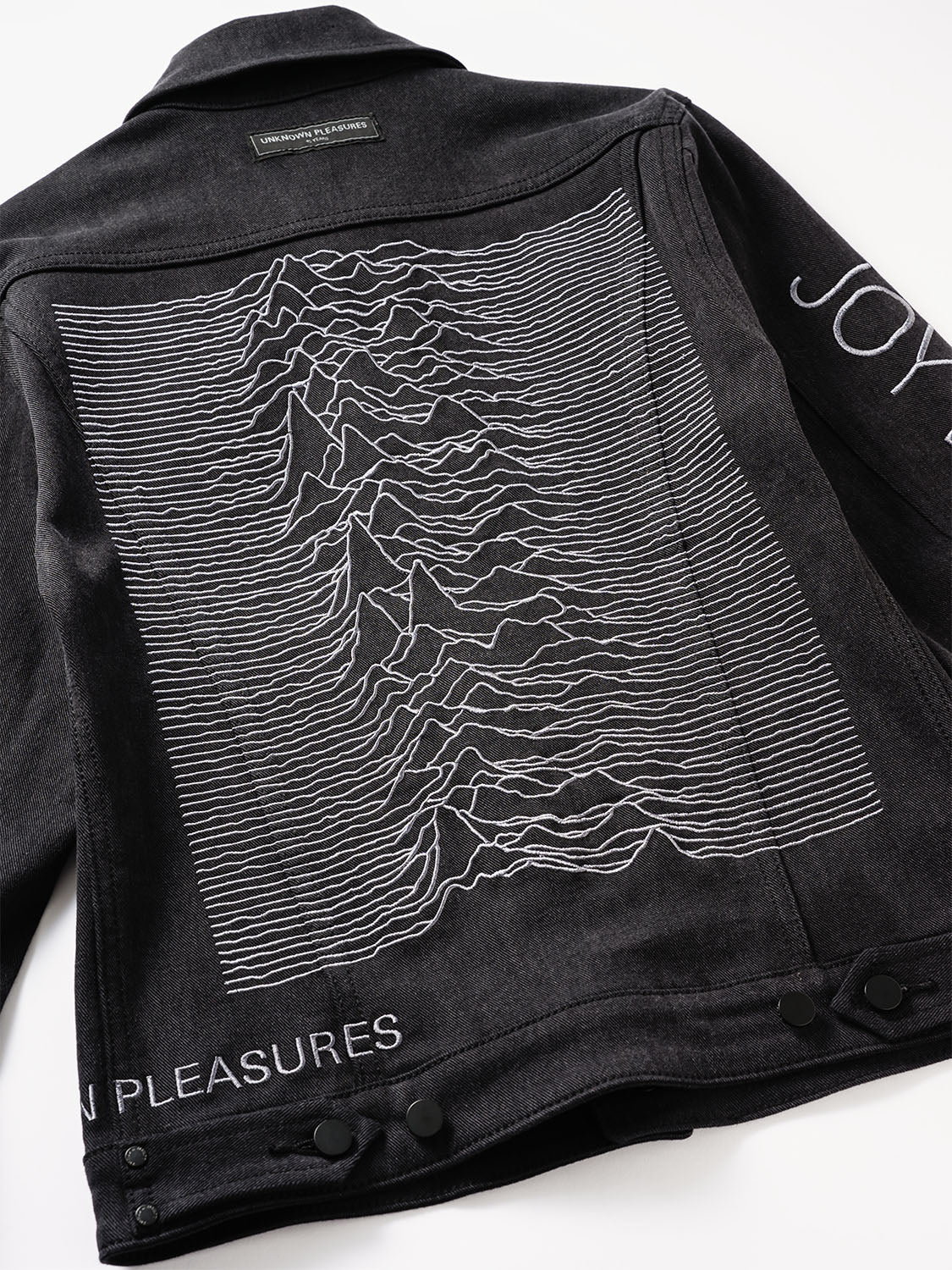 Angled view of the back panel displaying the waveform embroidery and sleeve detail.