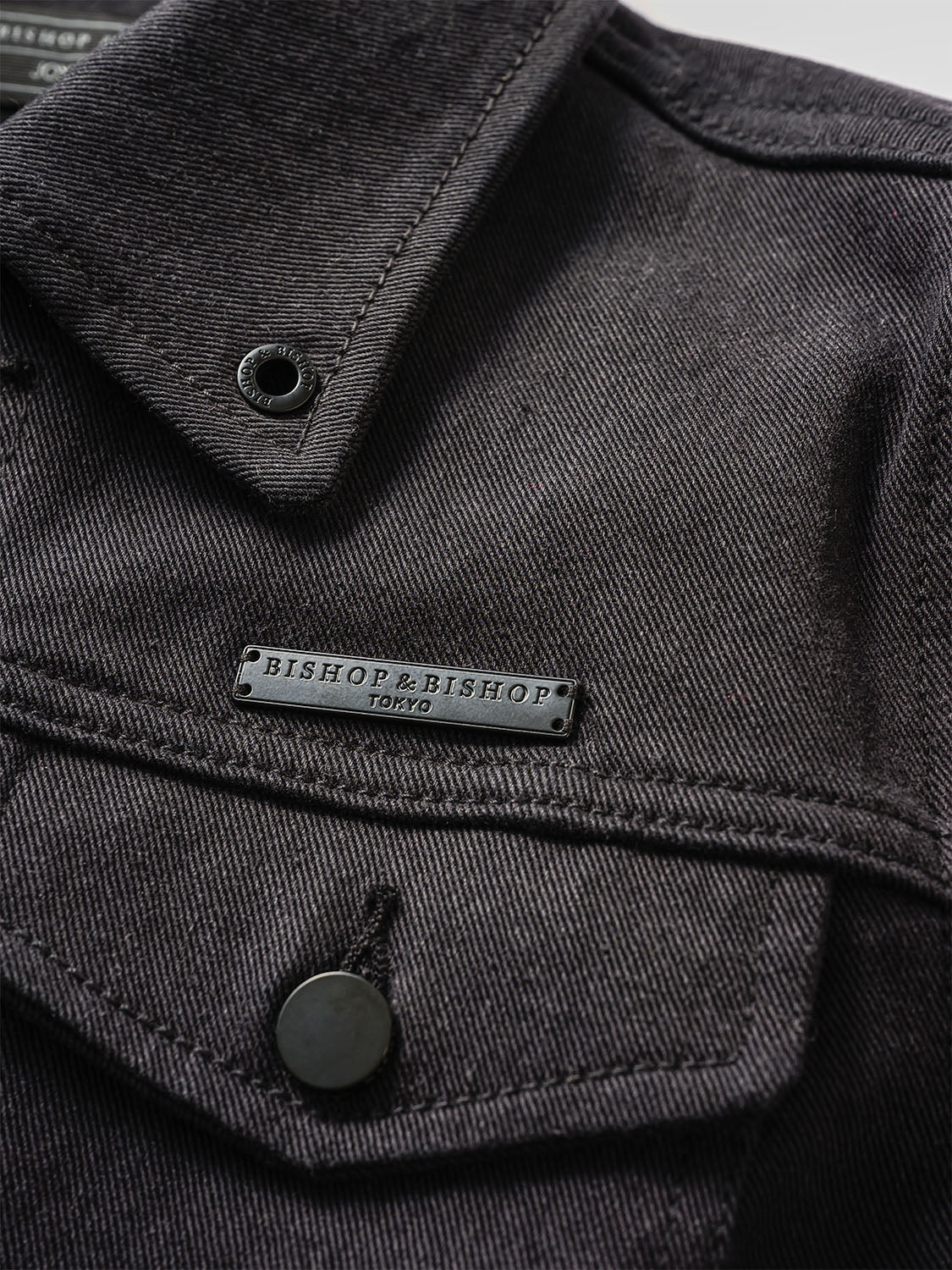 Zoomed-in image of the collar area with stitched black brand tag on faded denim.