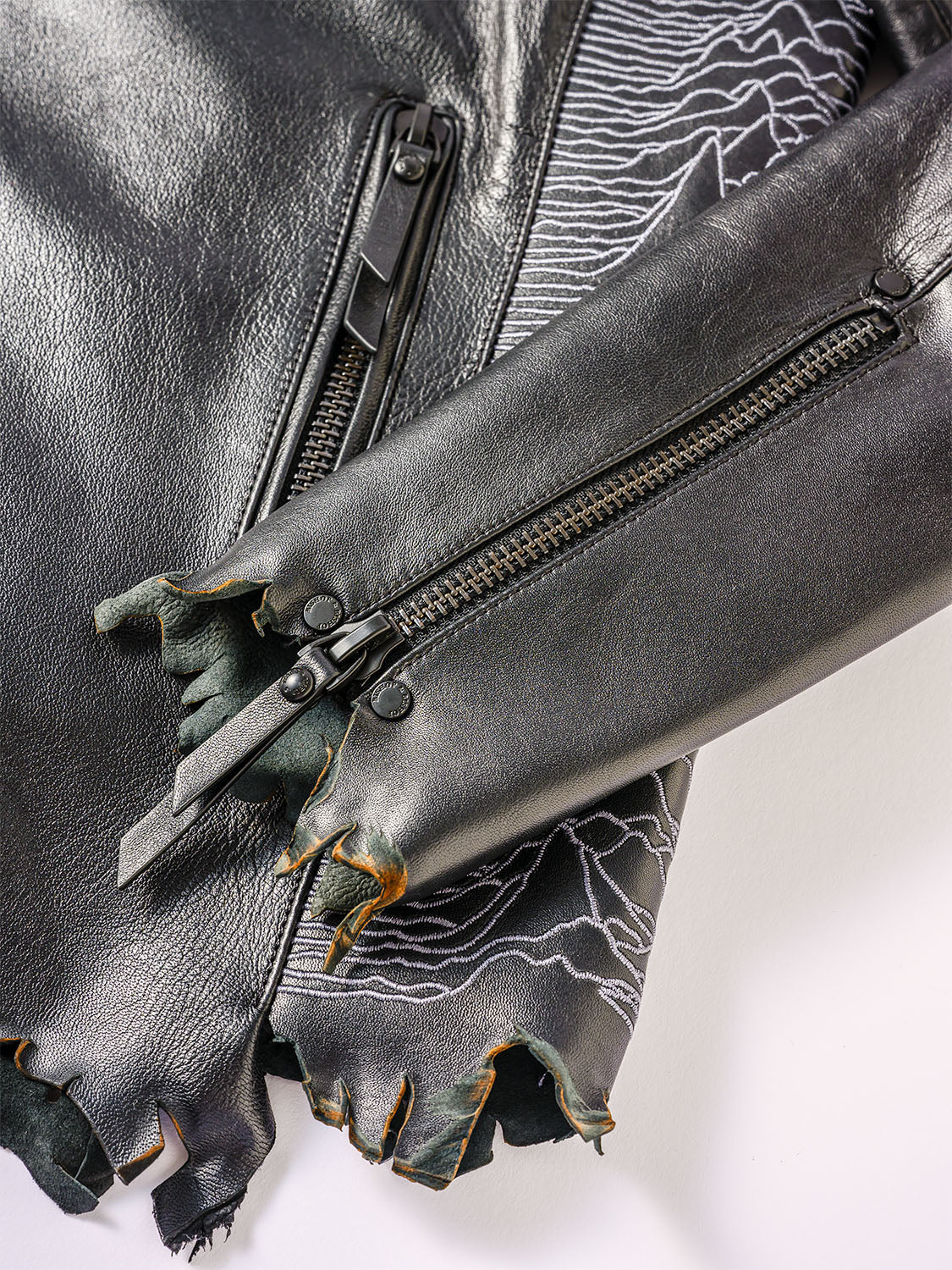 Zoomed-in view of the frayed zipper hem and fine stitching details on the leather edge.