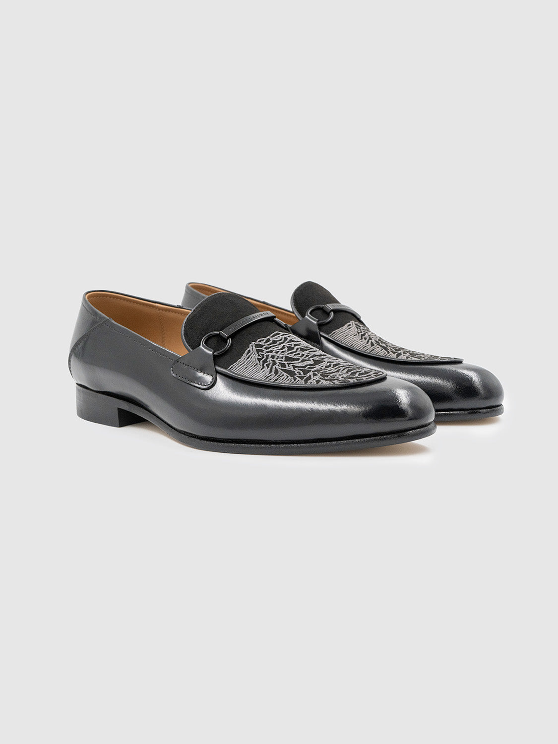 Angled side view of the black leather loafers showcasing the sleek profile and suede tongue.