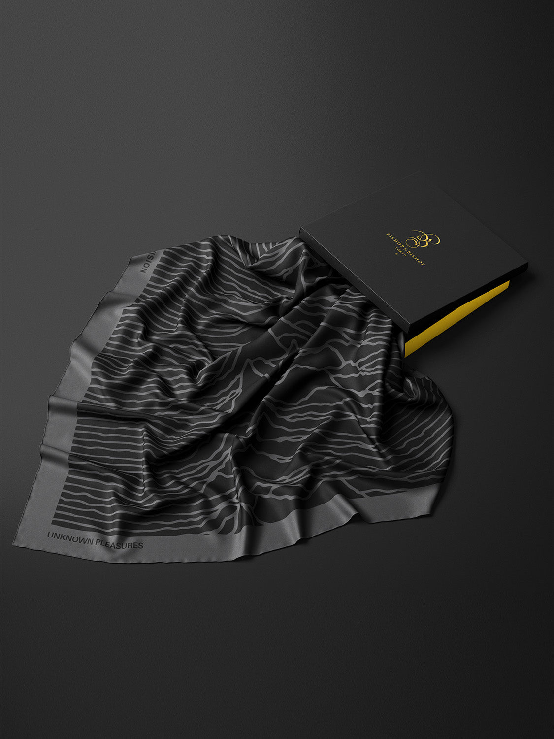 Crumpled presentation of the shawl next to a black and yellow box, emphasizing its soft drape and size.