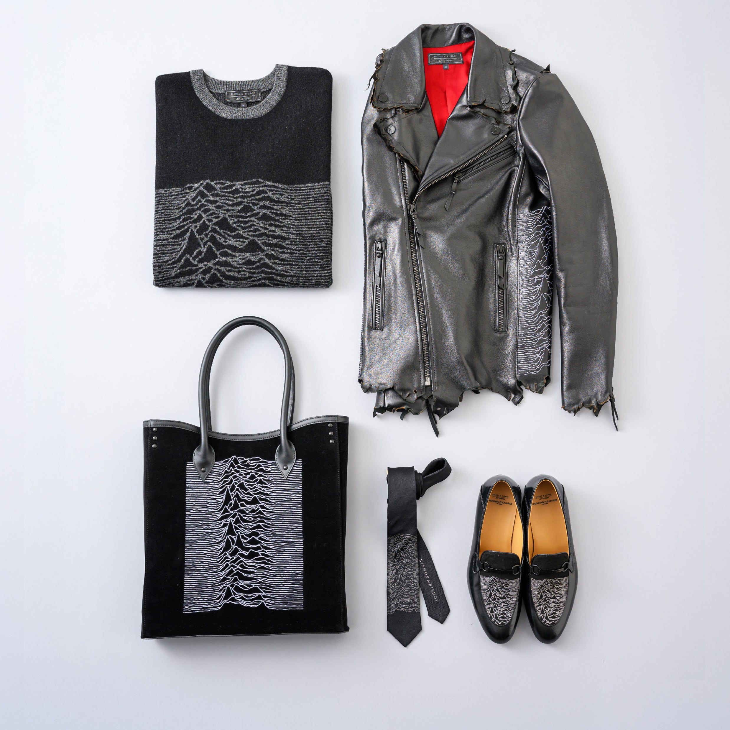 Minimalist image of a grey sweater, bag, shoes, tie, and leather jacket, all featuring the same motif, neatly folded and arranged on a light background.