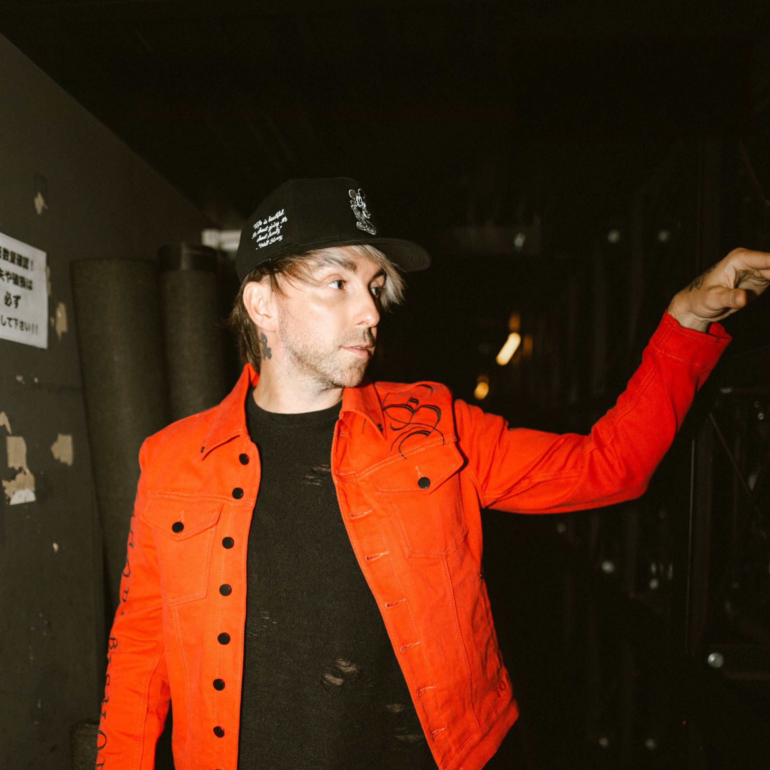 Front view of Alex Gaskarth wearing the custom red jacket, showcasing its bold color, sleek modern cut, and refined detailing that reflect his signature style.