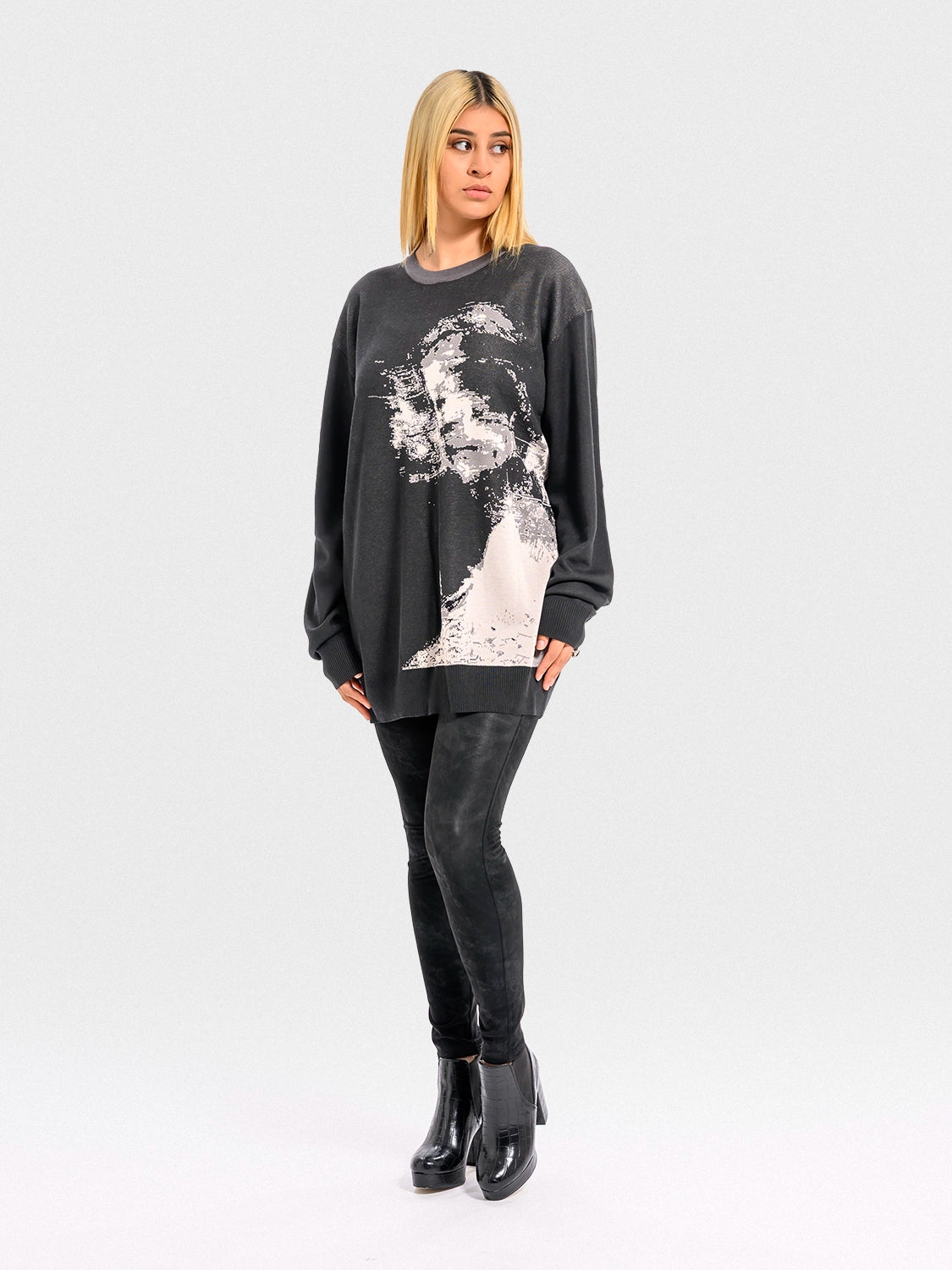 Person wearing a dark gray sweatshirt with a graphic design on a white background