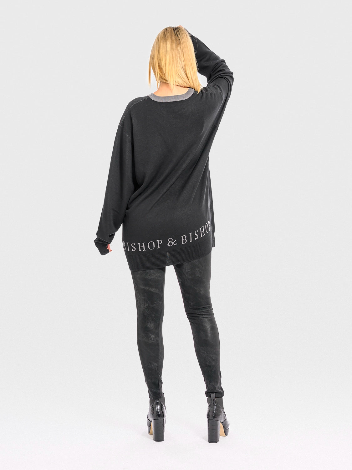 Person wearing a black long-sleeve top with 'Bishop & Bishop' branding on the back, standing against a light gray background.