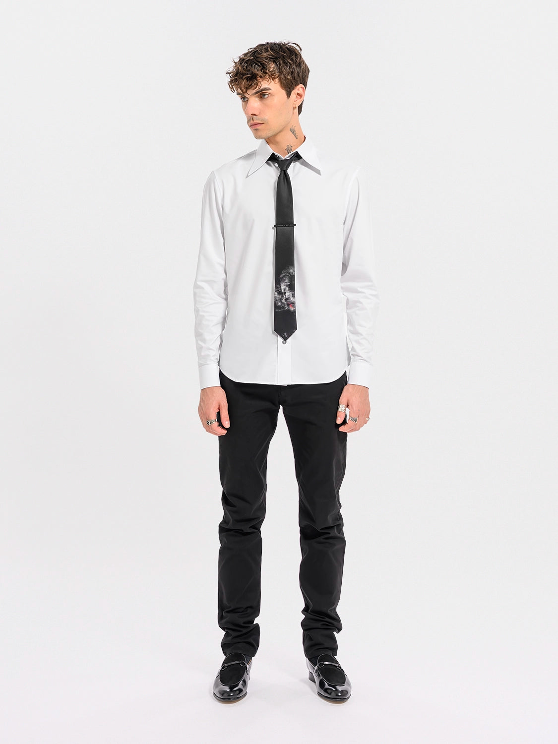 Man wearing a white dress shirt with a black tie and black pants on a white background