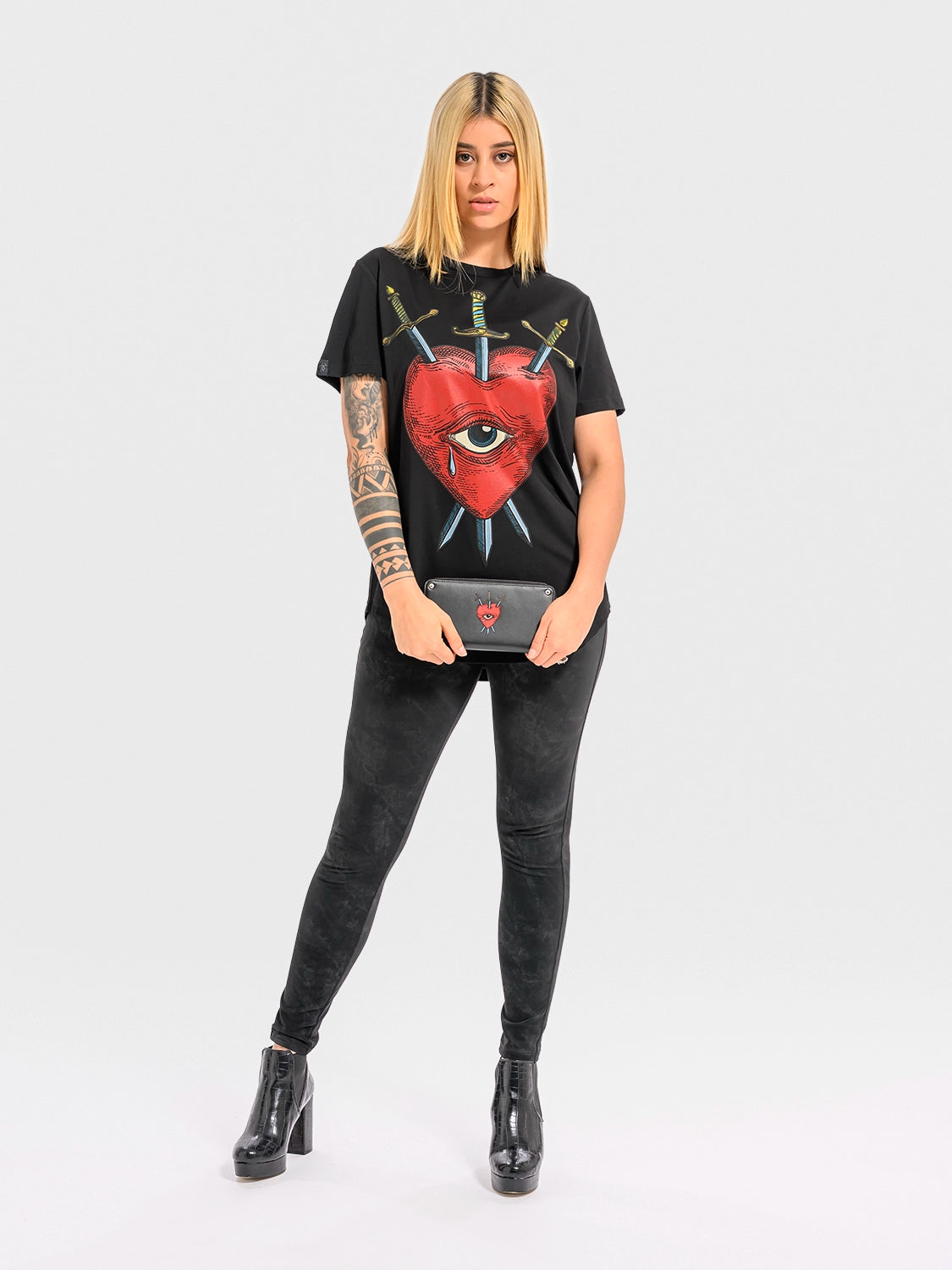 Person wearing a black t-shirt witha red heart, an eye, and crossed swords on a white background