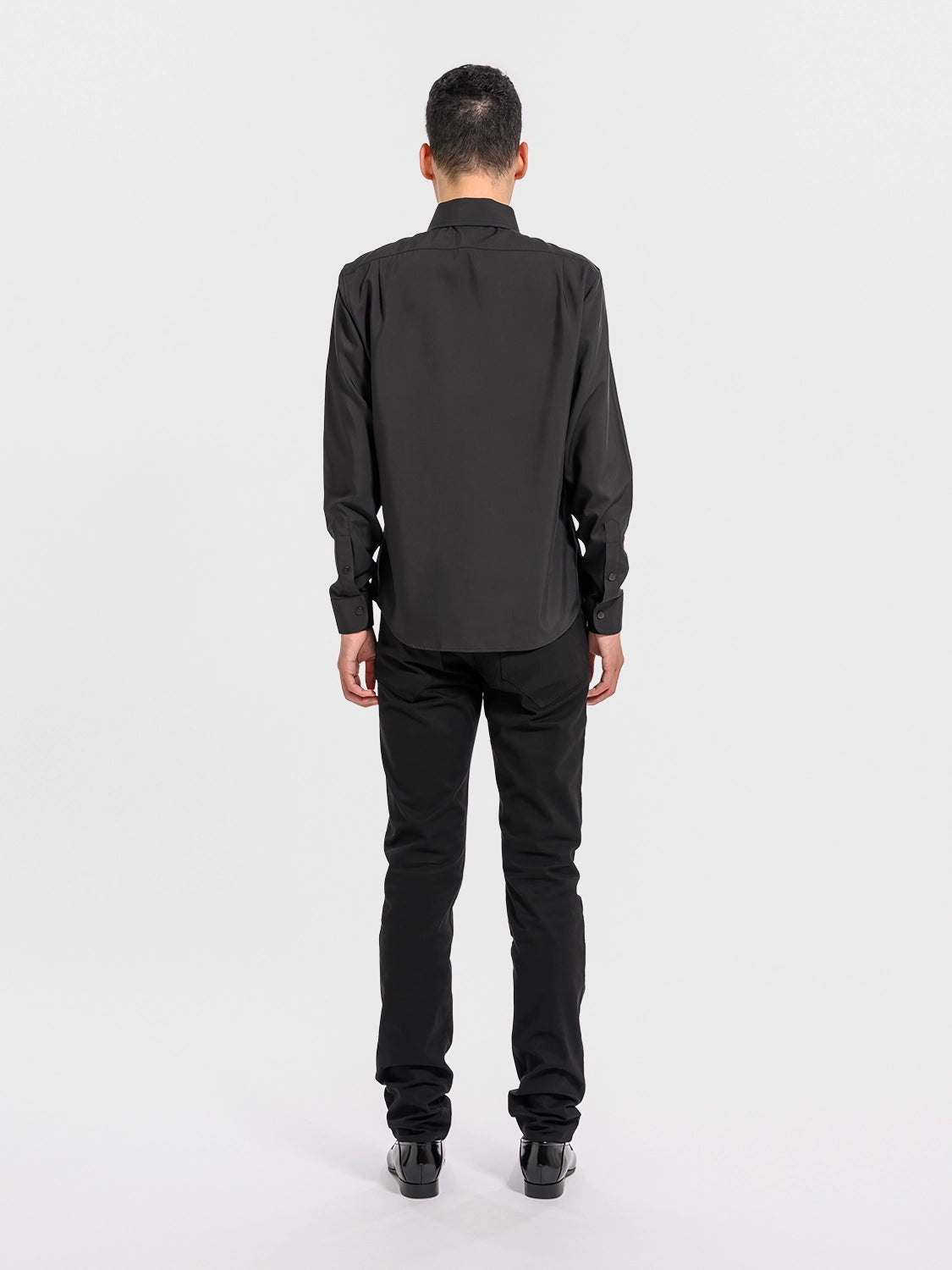 Person wearing a black shirt and pants on a white background