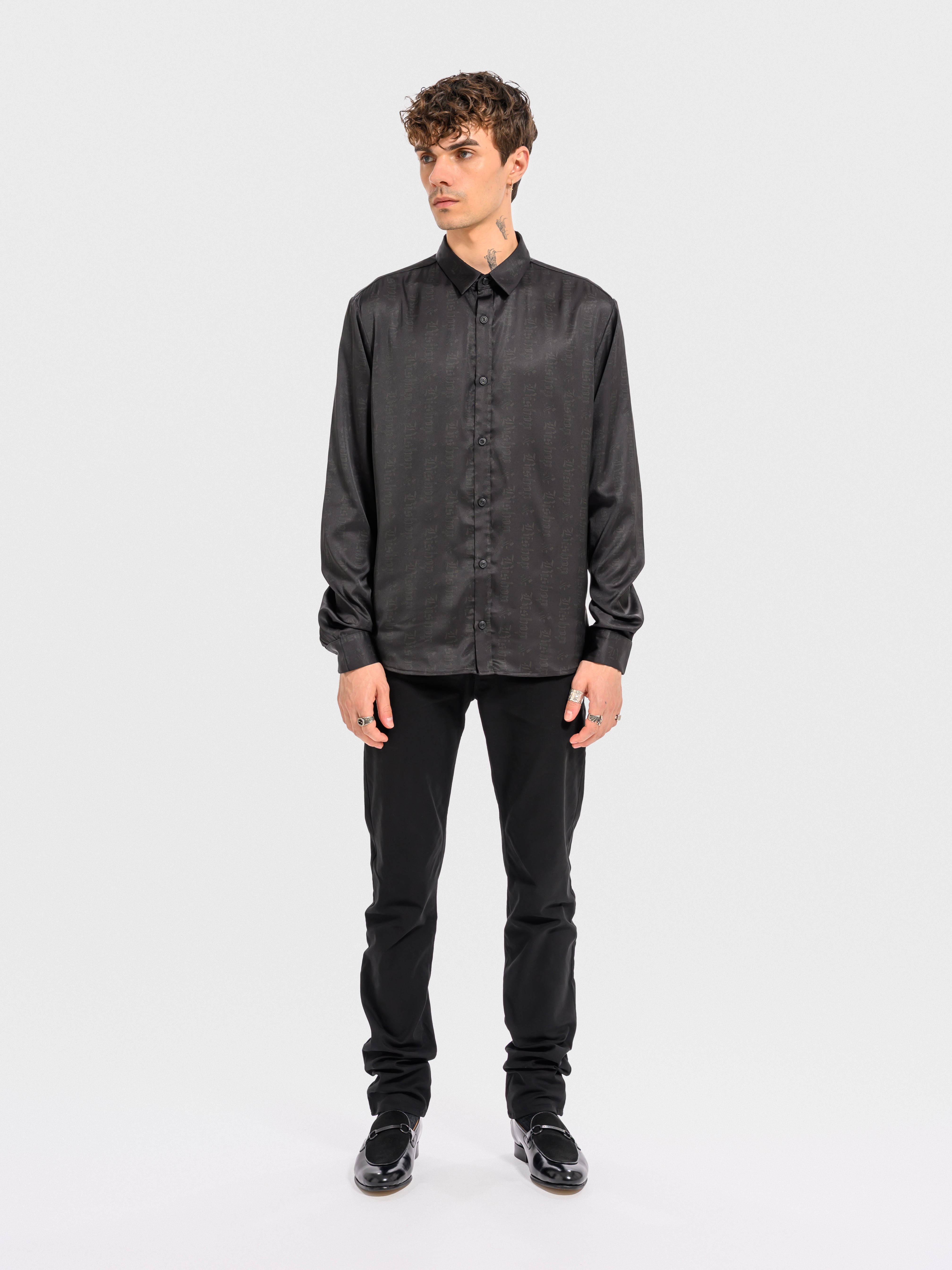 Man wearing a black button-up shirt and pants on a white background