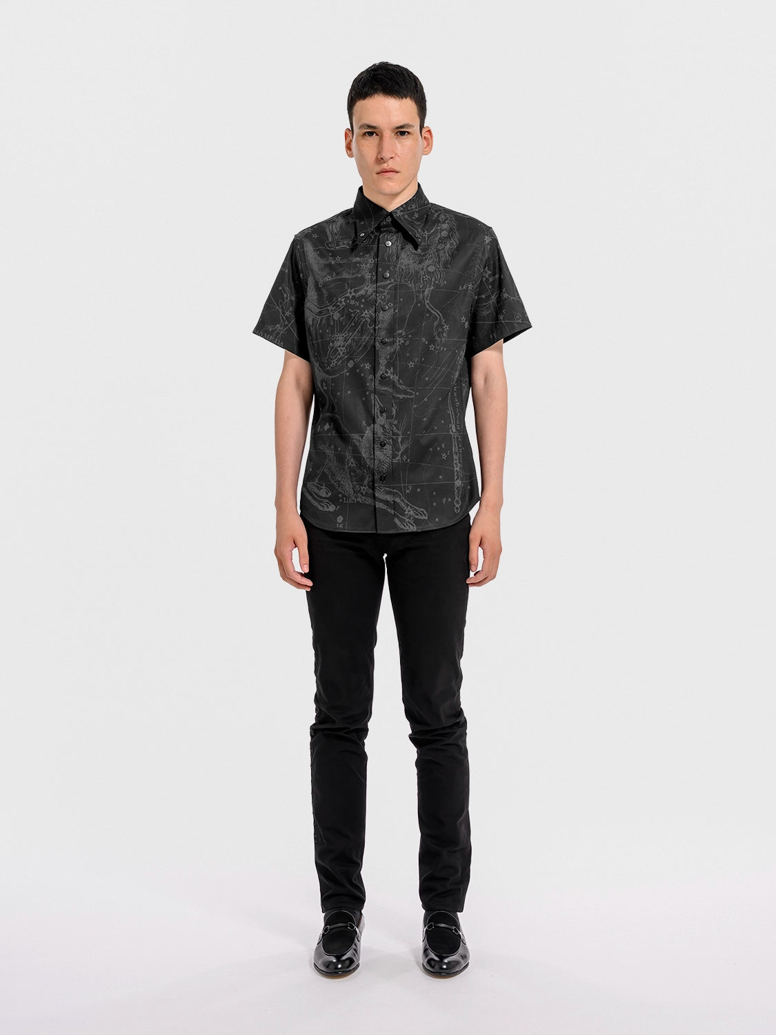 Person wearing a black patterned shirt and black pants on a white background