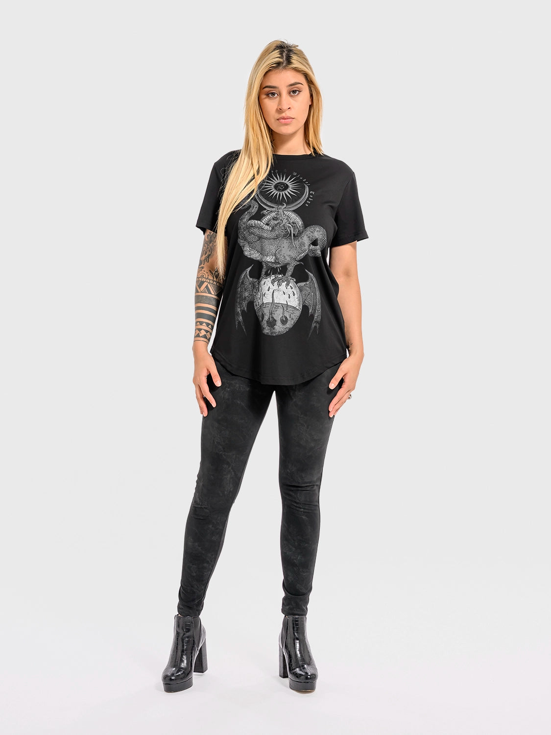 Woman wearing a black cotton 'Rebirth' T‑shirt with a graphic design and black pants on a white background