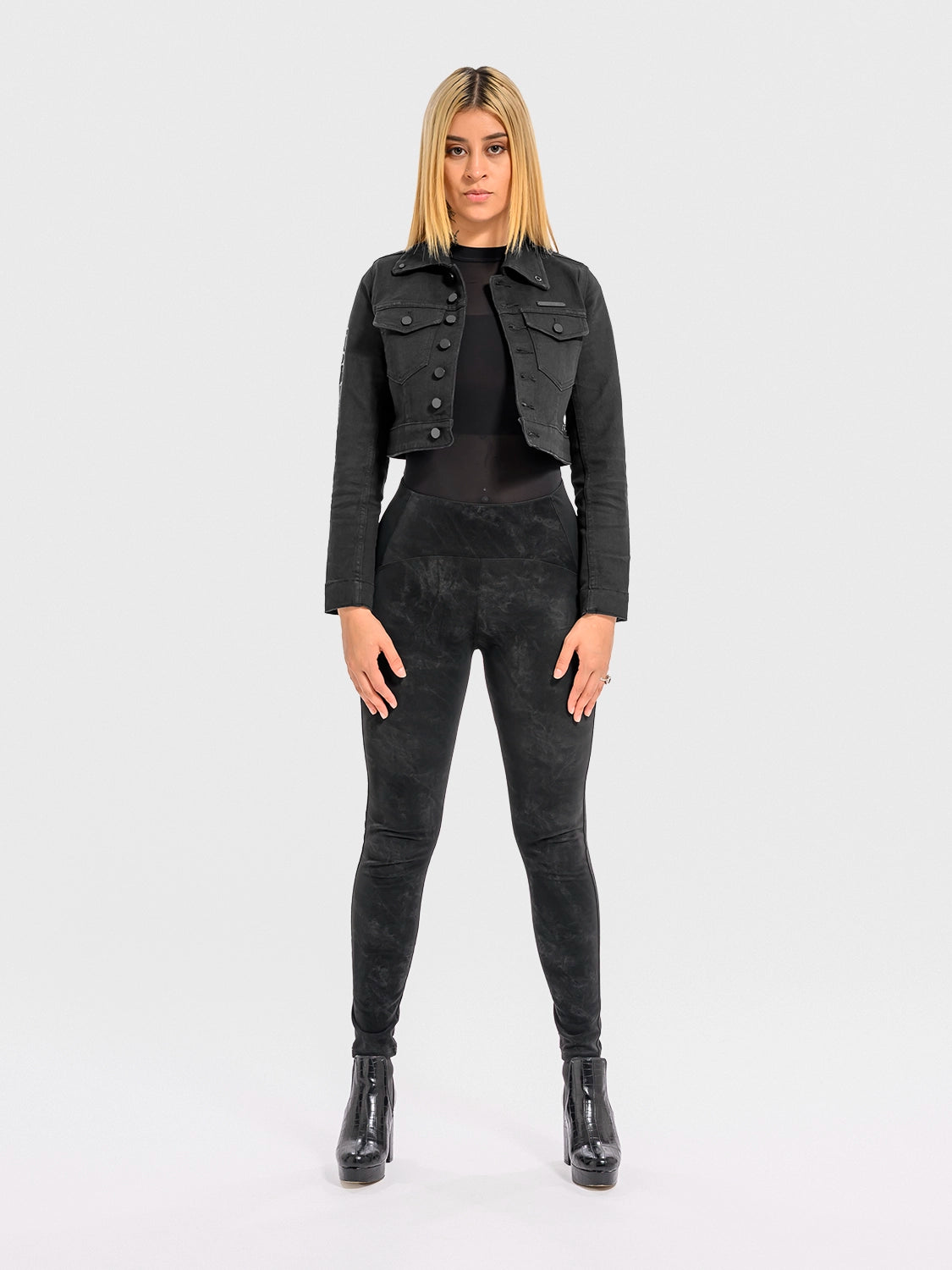 Woman wearing a black denim jacket and pants on a white background